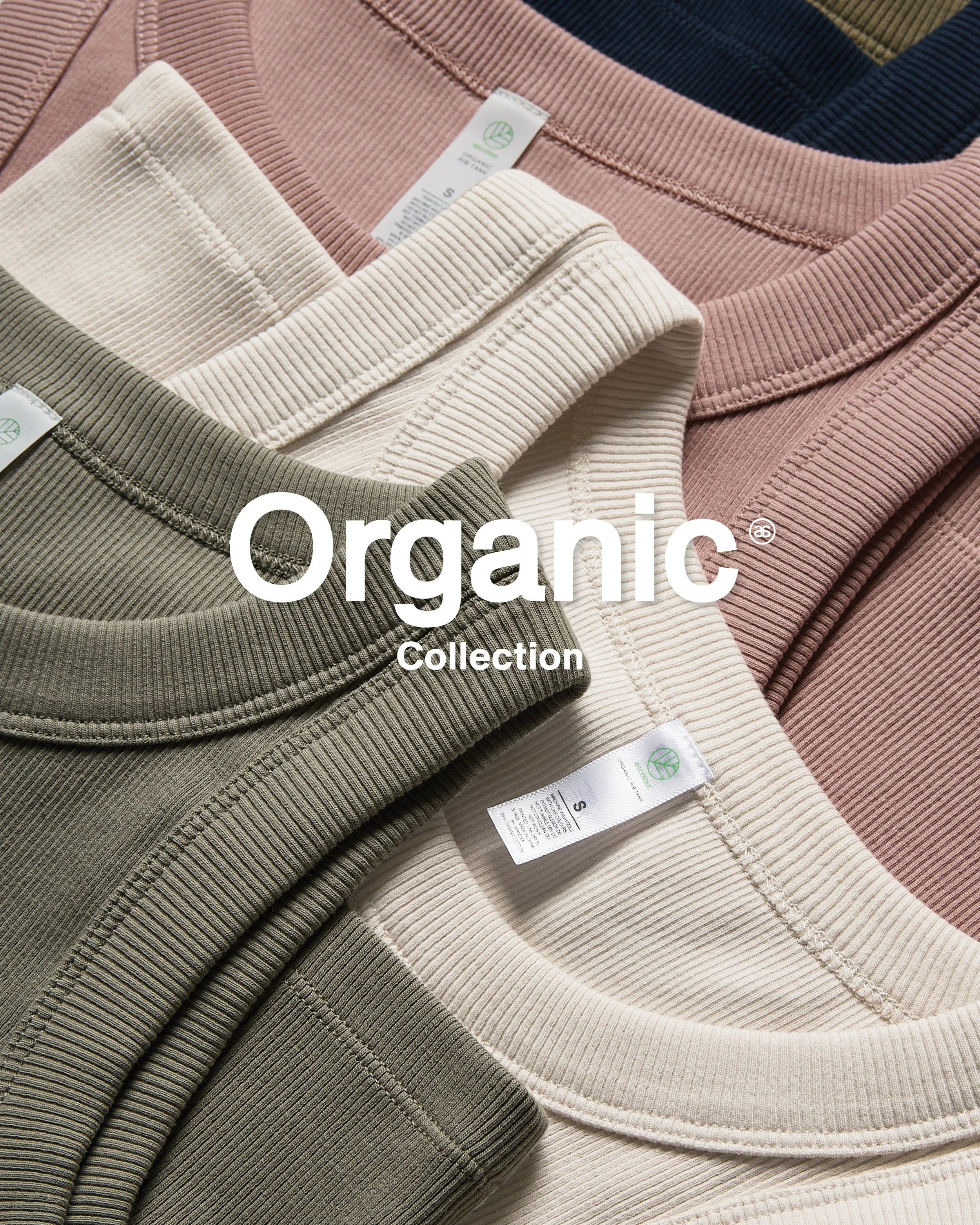 Stacked ribbed crewneck sweatshirts in beige, pink, olive, and cream colors, with visible tags indicating they are organic, laid out on a flat surface.