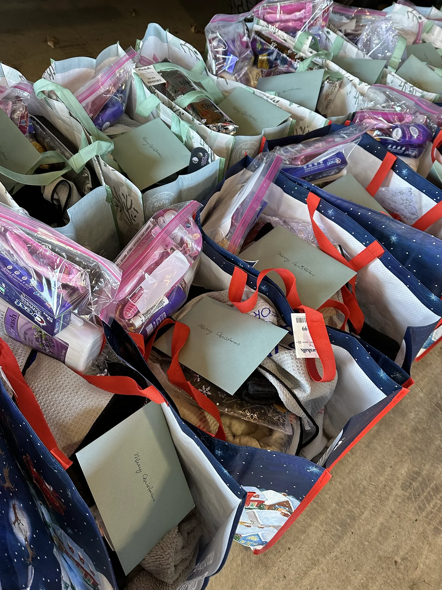 Holiday gift bags filled with personal care items, clothing, and handwritten cards prepared for donation.
