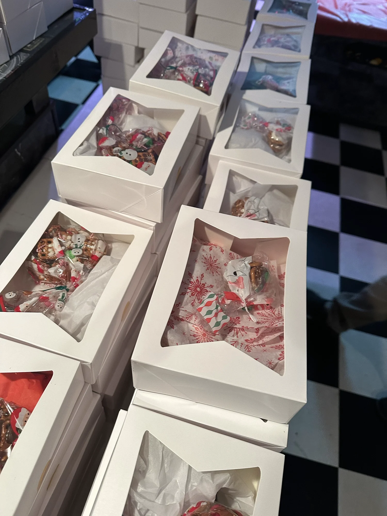 White bakery boxes filled with holiday treats stacked and ready for gifting or distribution.
