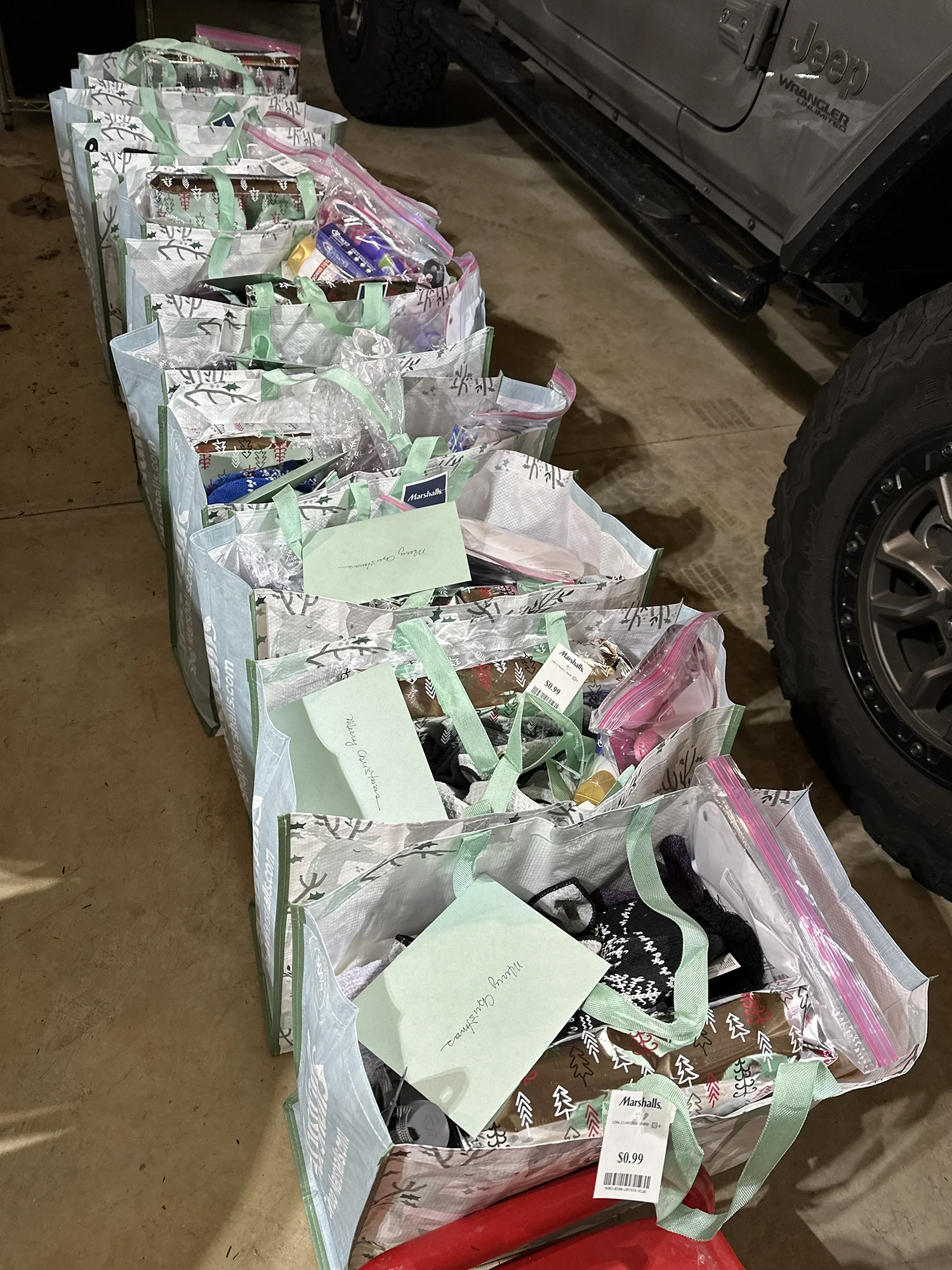 Row of holiday donation bags filled with gifts and labeled for individual recipients.