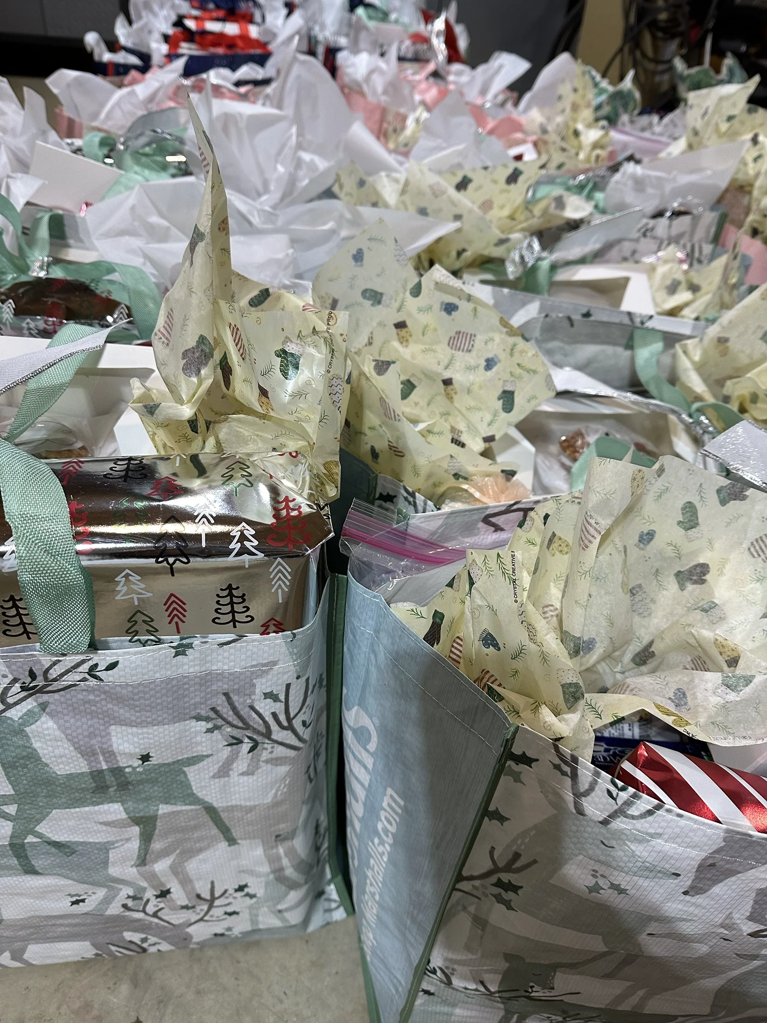 Holiday gift bags filled with wrapped presents and supplies prepared for community distribution.