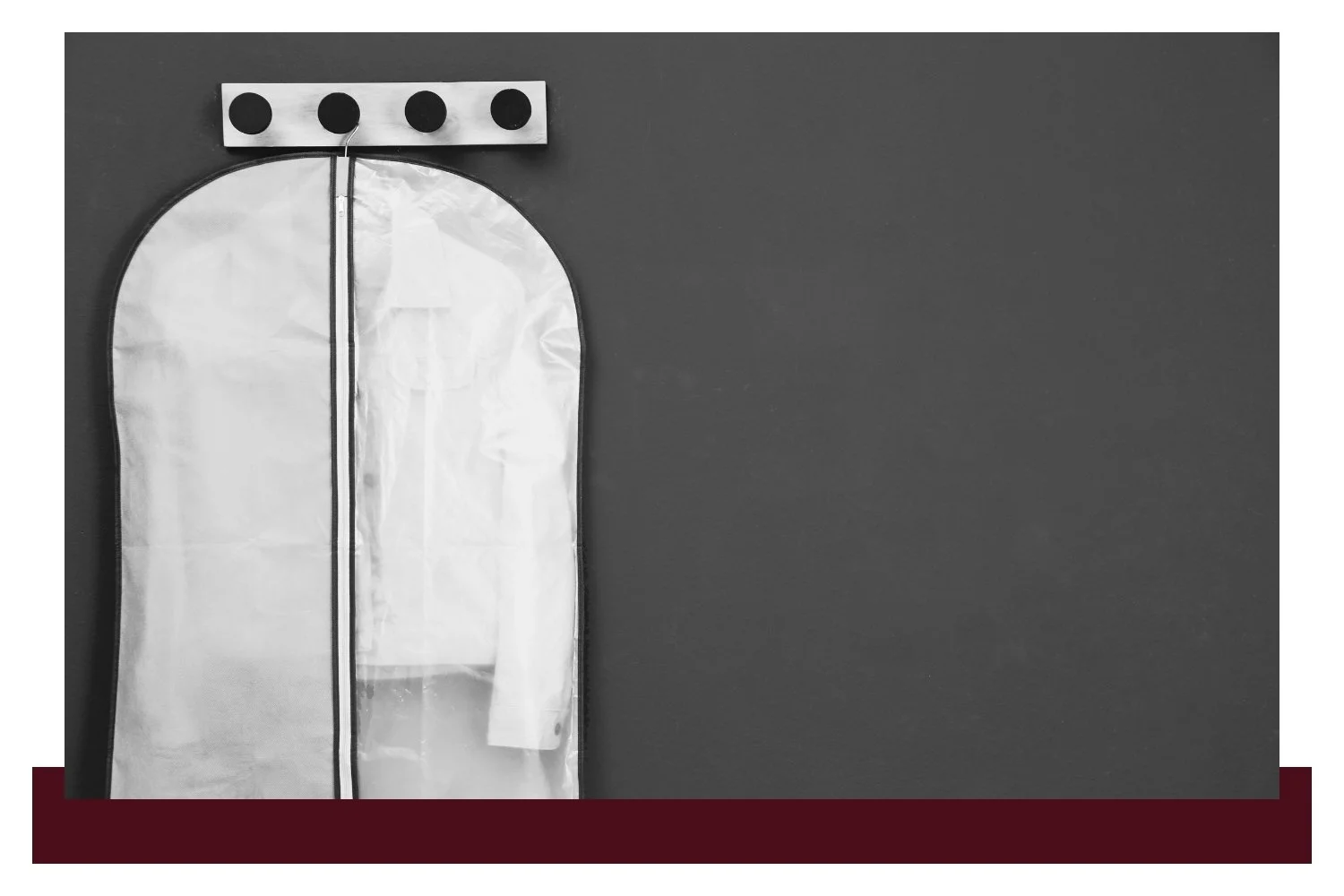 Black-and-white view of a tall white bag with a rounded top, hung from a horizontal bar with four dark circular fasteners, against a dark background with empty space to the right.