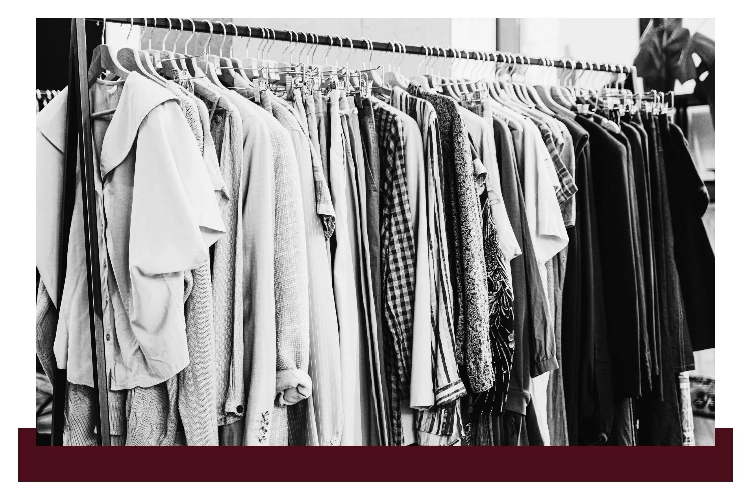 Rows of neatly hung shirts and jackets on a clothing rack, shown in black and white, with various textures and patterns ranging from solid colors to checkered and patterned fabrics.