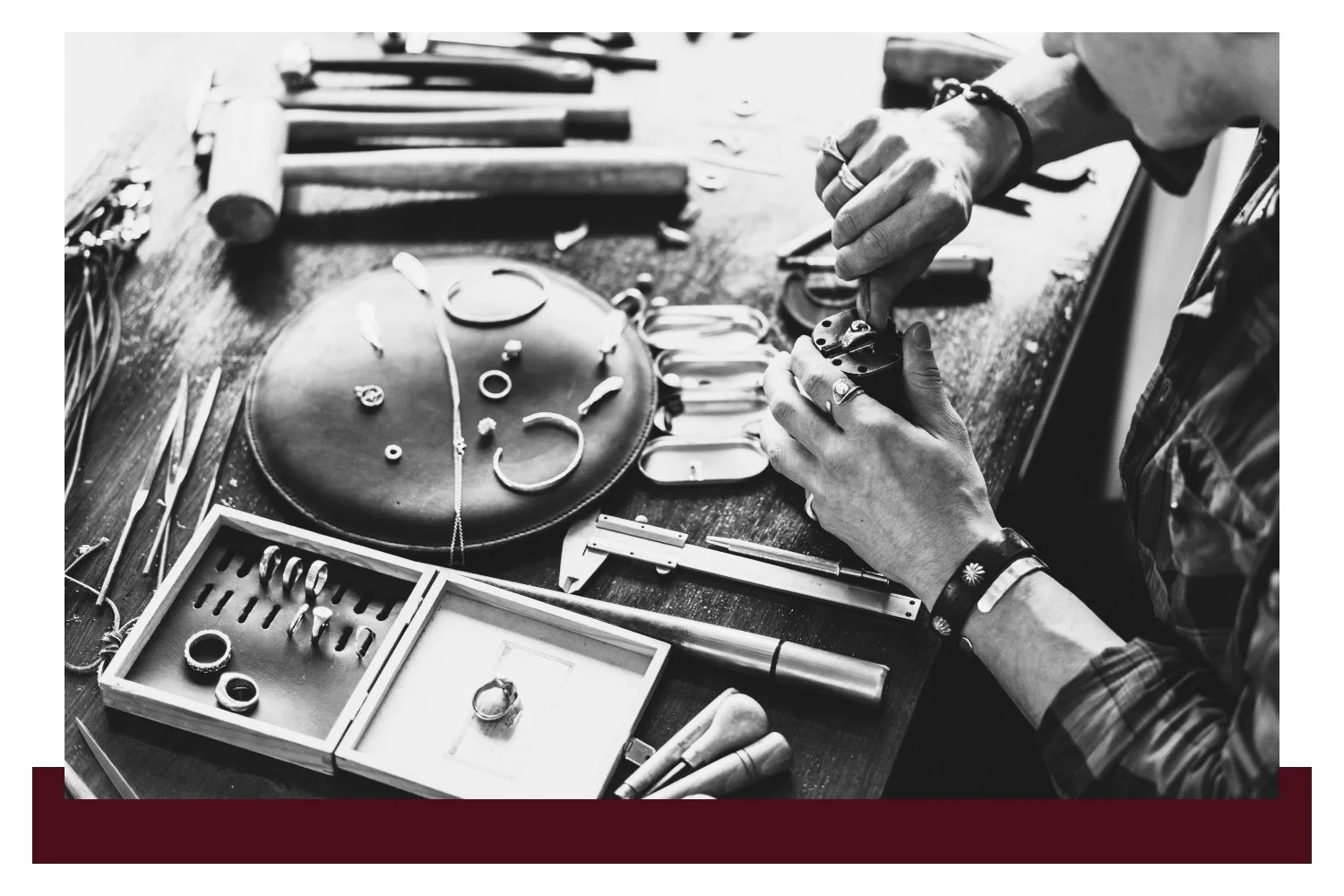 A person in a workshop uses a tool to assemble a metal circular part on a machine, with gauges and small components laid out on a workbench in the foreground.