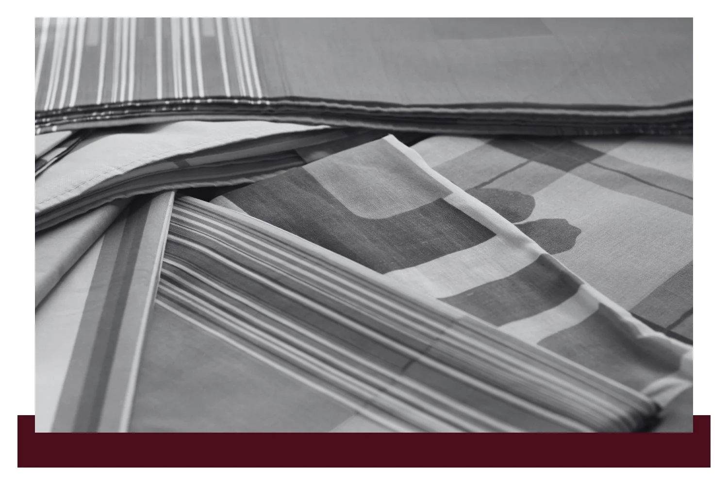 Close-up of a striped fabric and a folded checkered cloth, with a dark seam running along the edge against a light background.
