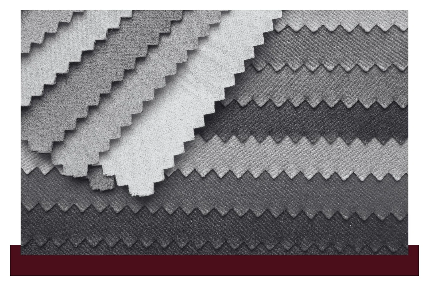 Overlapping fabric swatches in gray and dark blue with zigzag, scalloped edges, showing different textures and weave patterns.