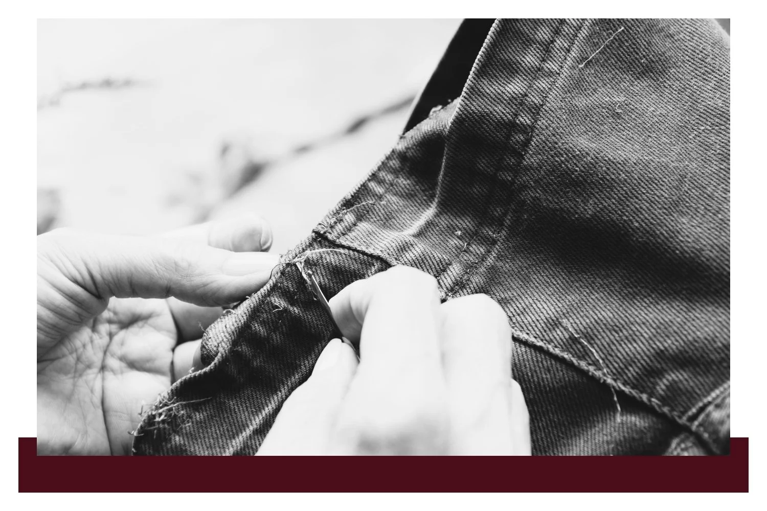 Close-up of hands adjusting the cuff of a gray denim jacket, with the fabric texture and stitching in sharp focus against a soft, blurred background.