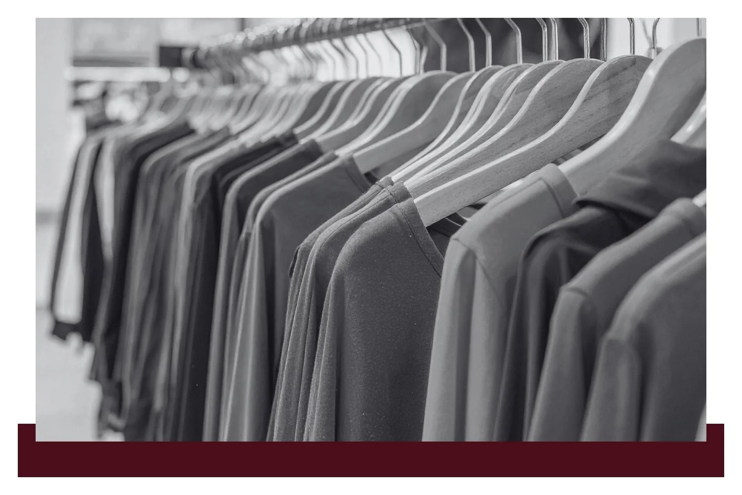 Rows of neatly hung shirts on metal hangers in a clothing rack, shown in black and white with close-up focus on the front garments.
