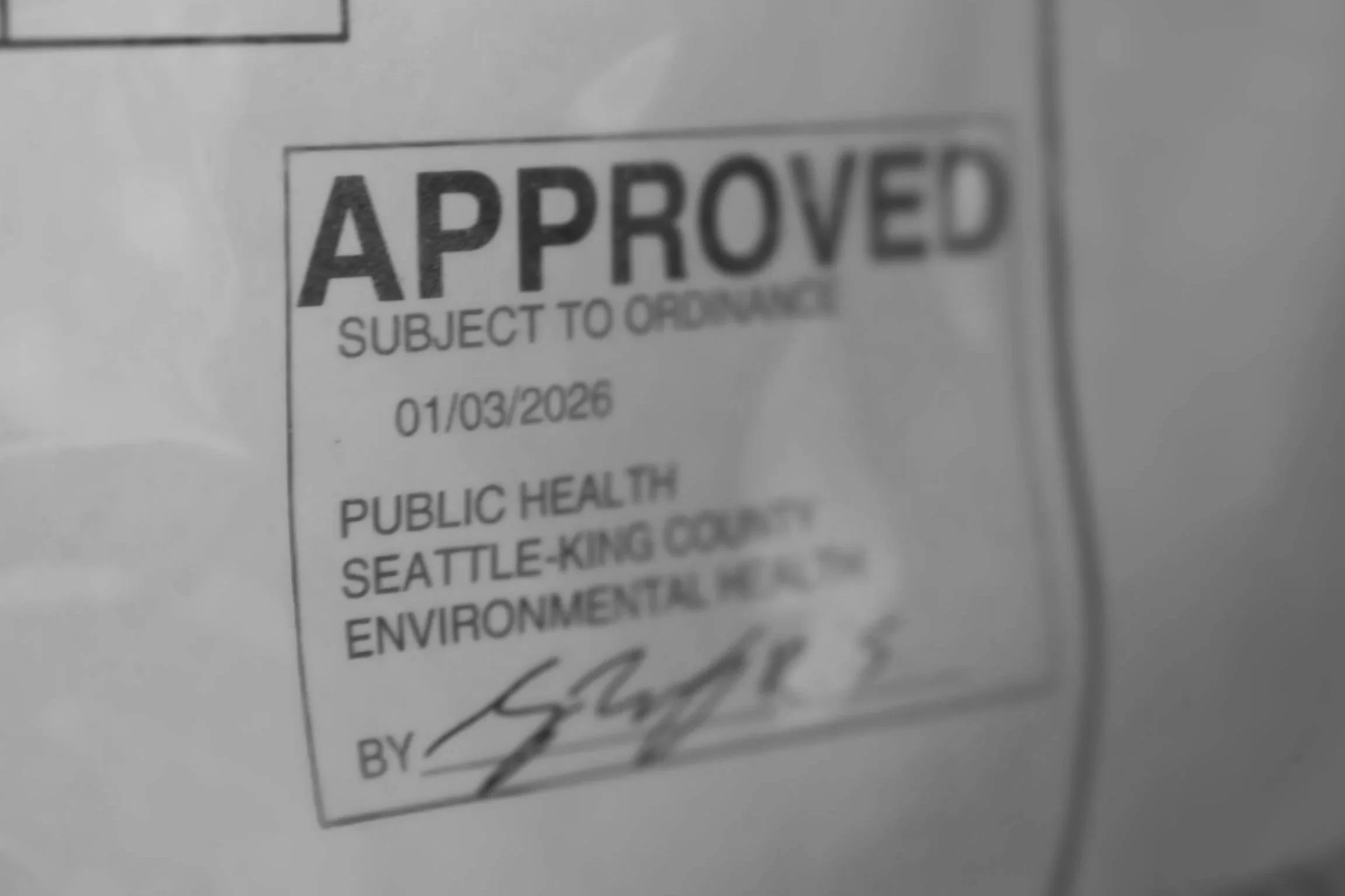 Close-up of an 'Approved' permit stamp for commercial building permit acquisition services in Seattle.
