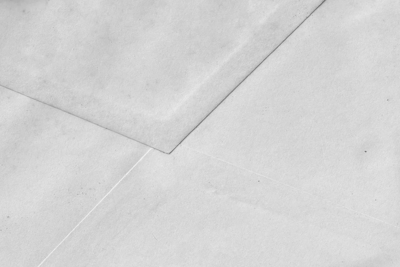 Close-up of a white paper envelope with a flap partially open, revealing the top corner of the glued flap.