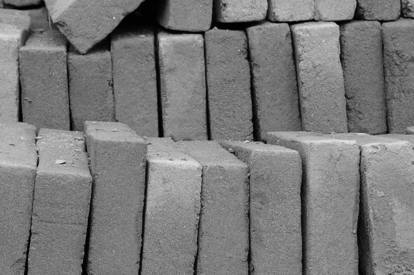 Stacked bricks in various orientations, close-up black and white photograph.