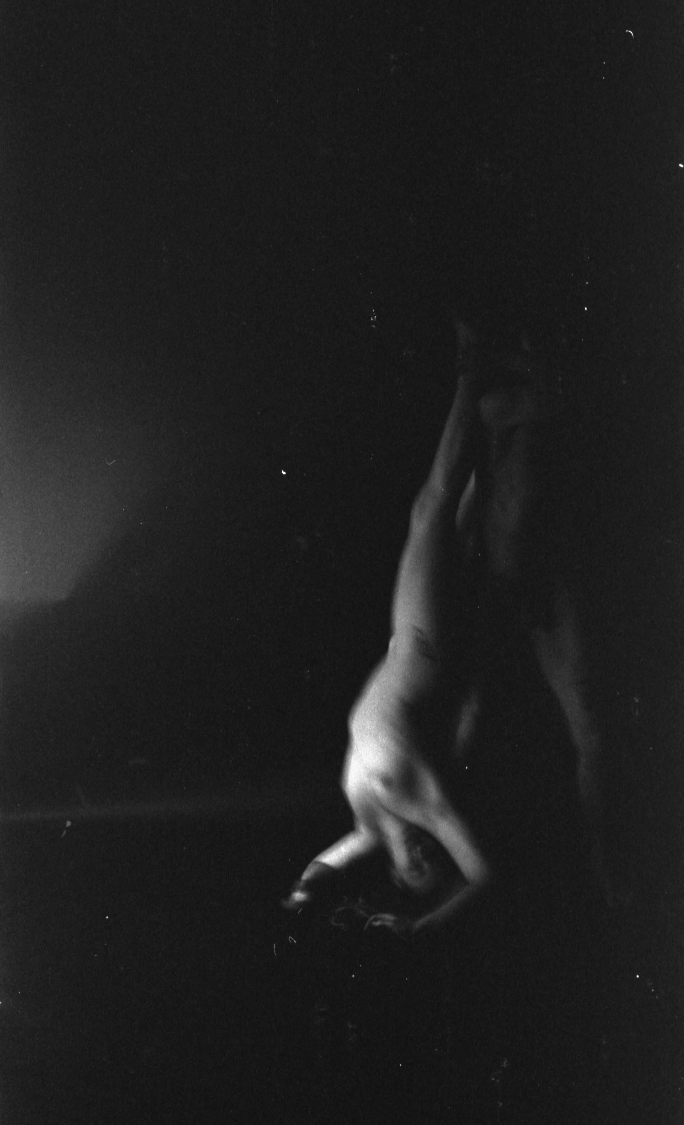 A black and white photo of a person emerging from water at night, with stars visible in the sky.