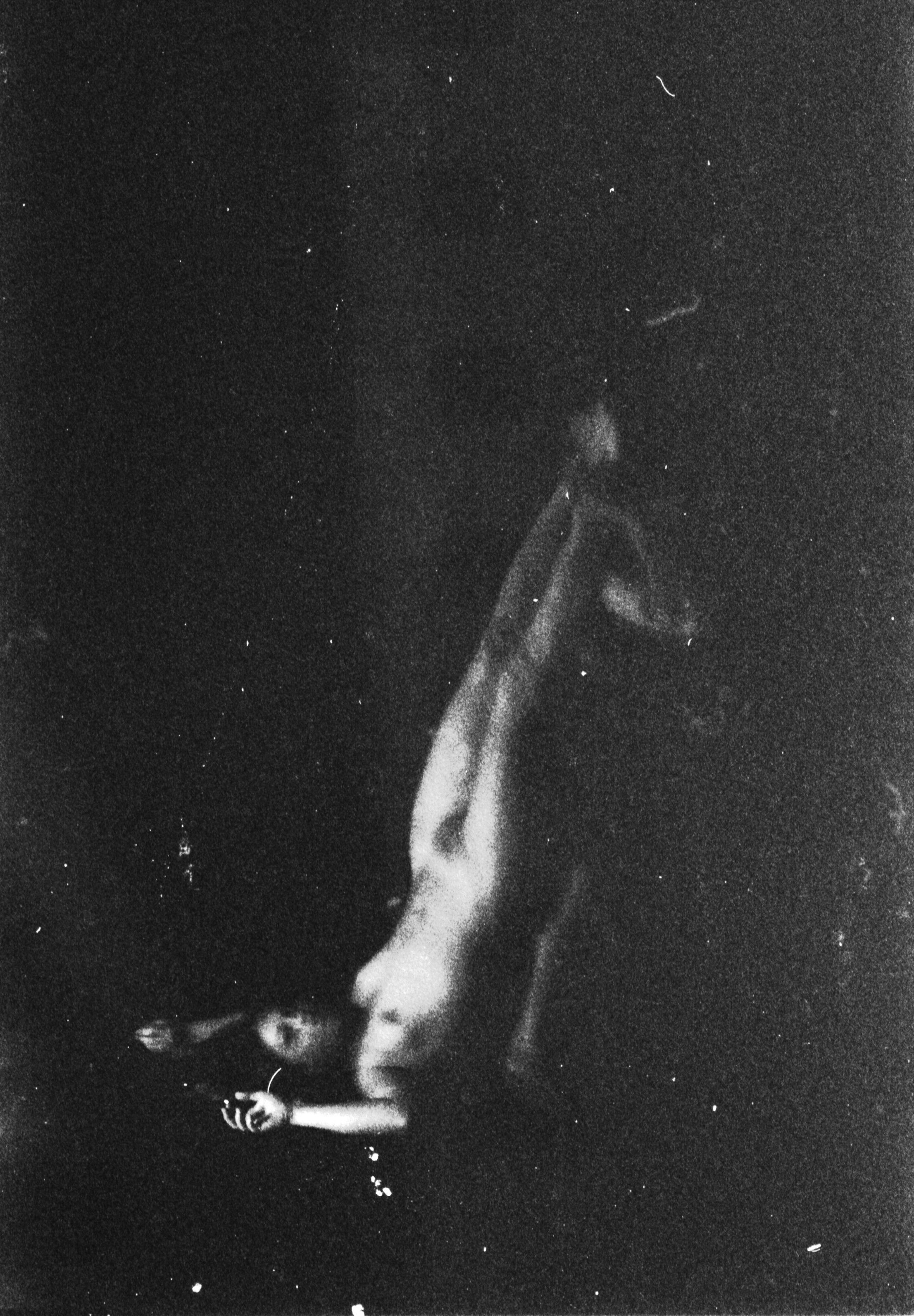Black and white photo of a woman reaching out towards stars in a dark starry sky.