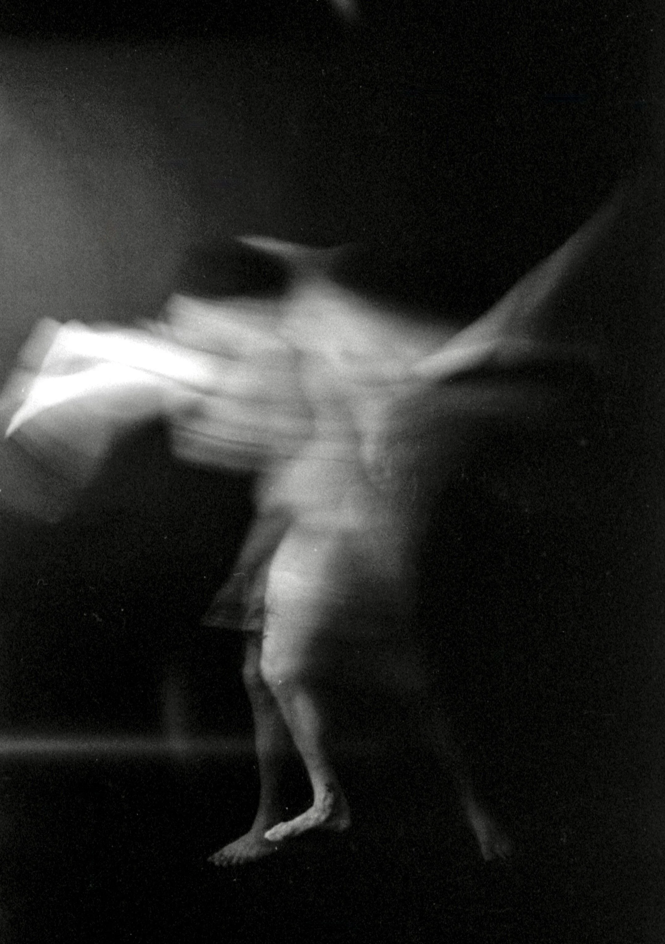 Black and white photo of a chicken standing against a dark background.