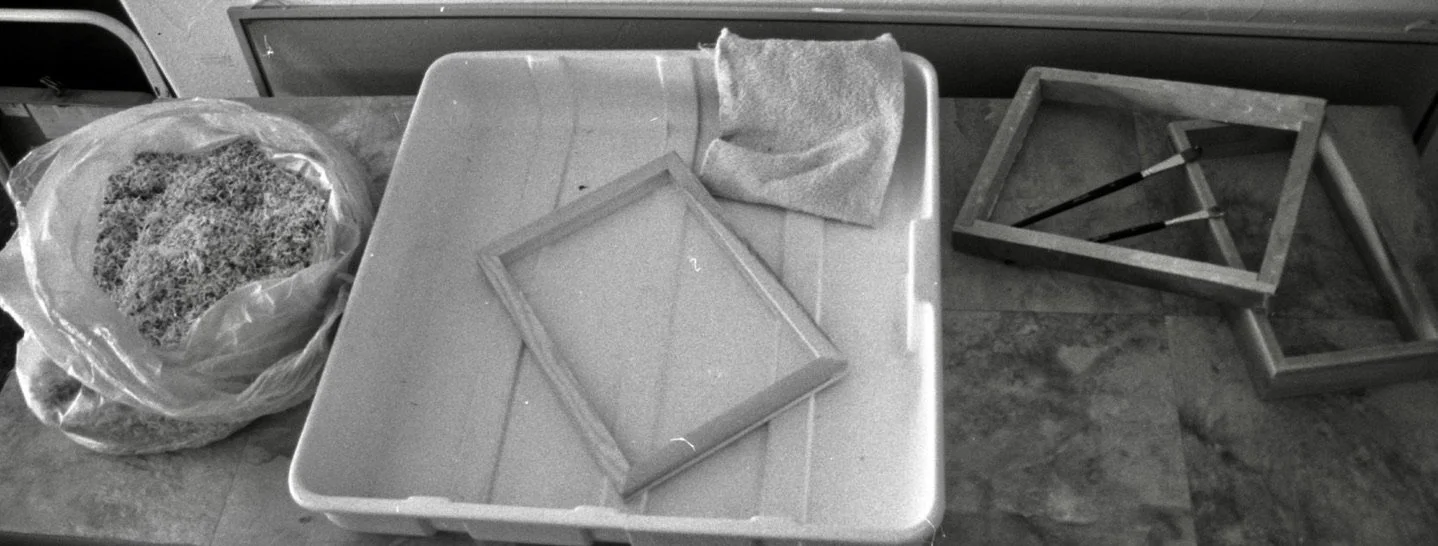 A cluttered kitchen countertop with various empty picture frames, a bag of shredded material, and a cloth.