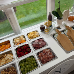 A mobile wooden cart styled with an assortment of cured meats, artisan cheeses, crackers, and fruits for a party grazing station