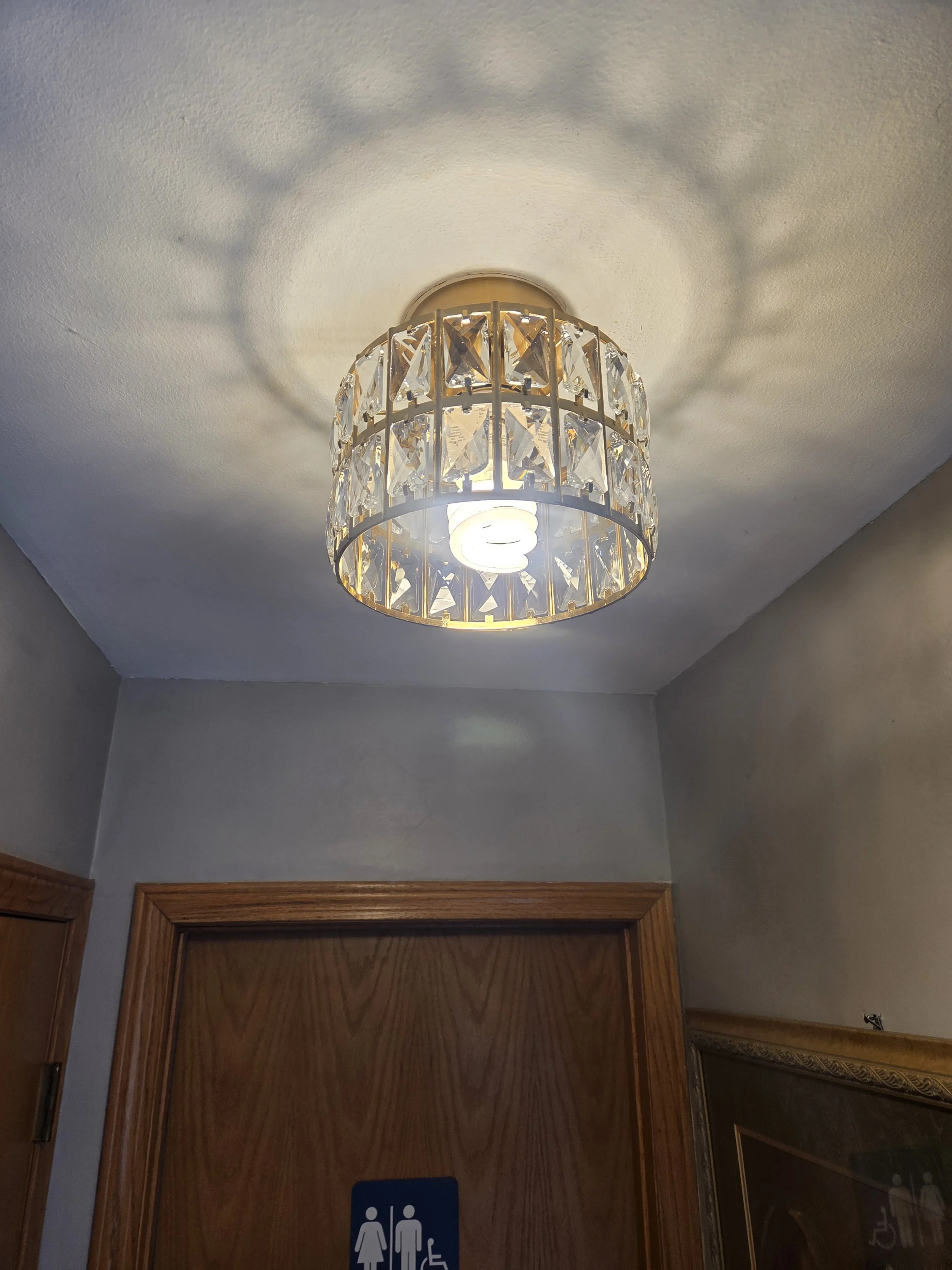 Ceiling light fixture with crystal-like decorations casting shadows on the ceiling.