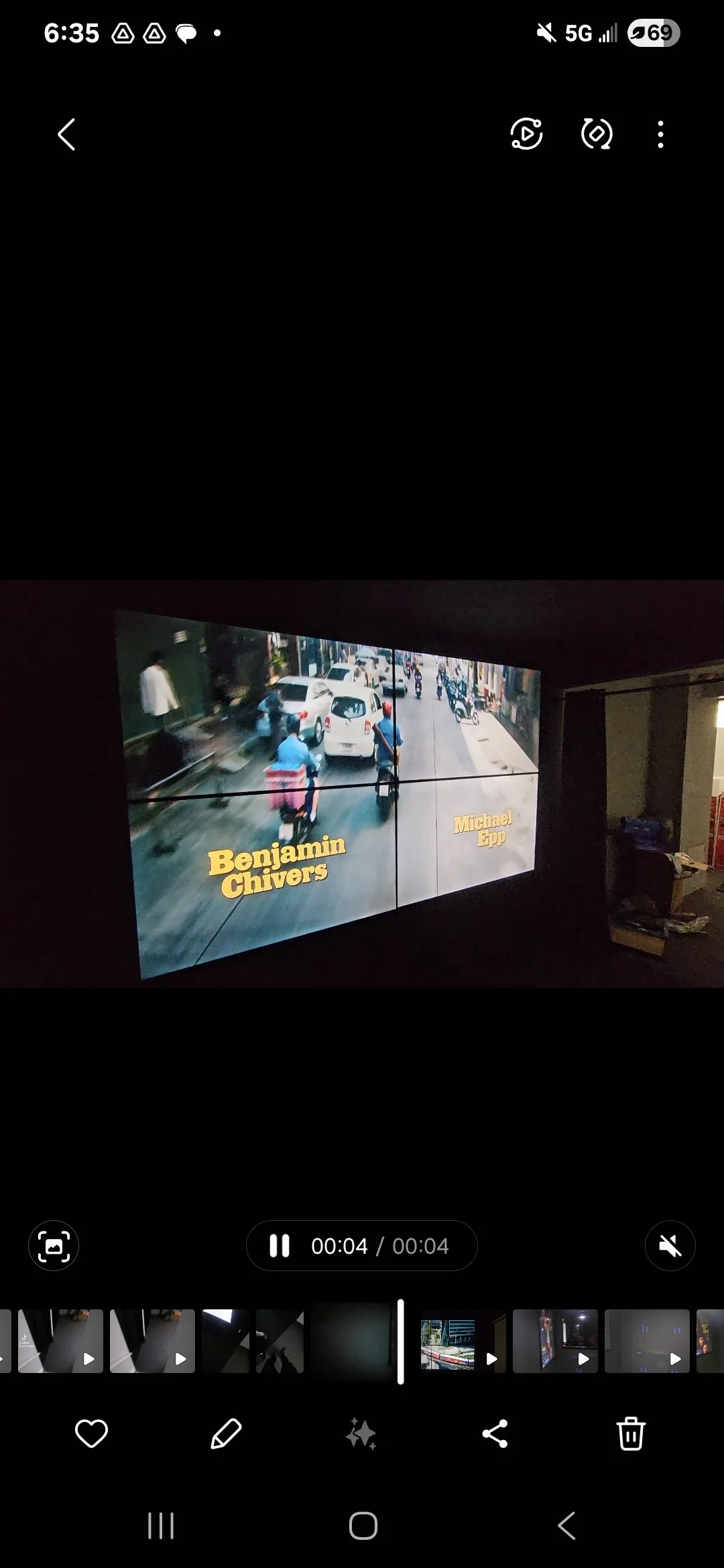 A video screen shows a street scene with cars, motorcycles, and pedestrians. At the bottom of the screen, yellow text displays the names 'Benjamin Chivers' and 'Michael Epp.'