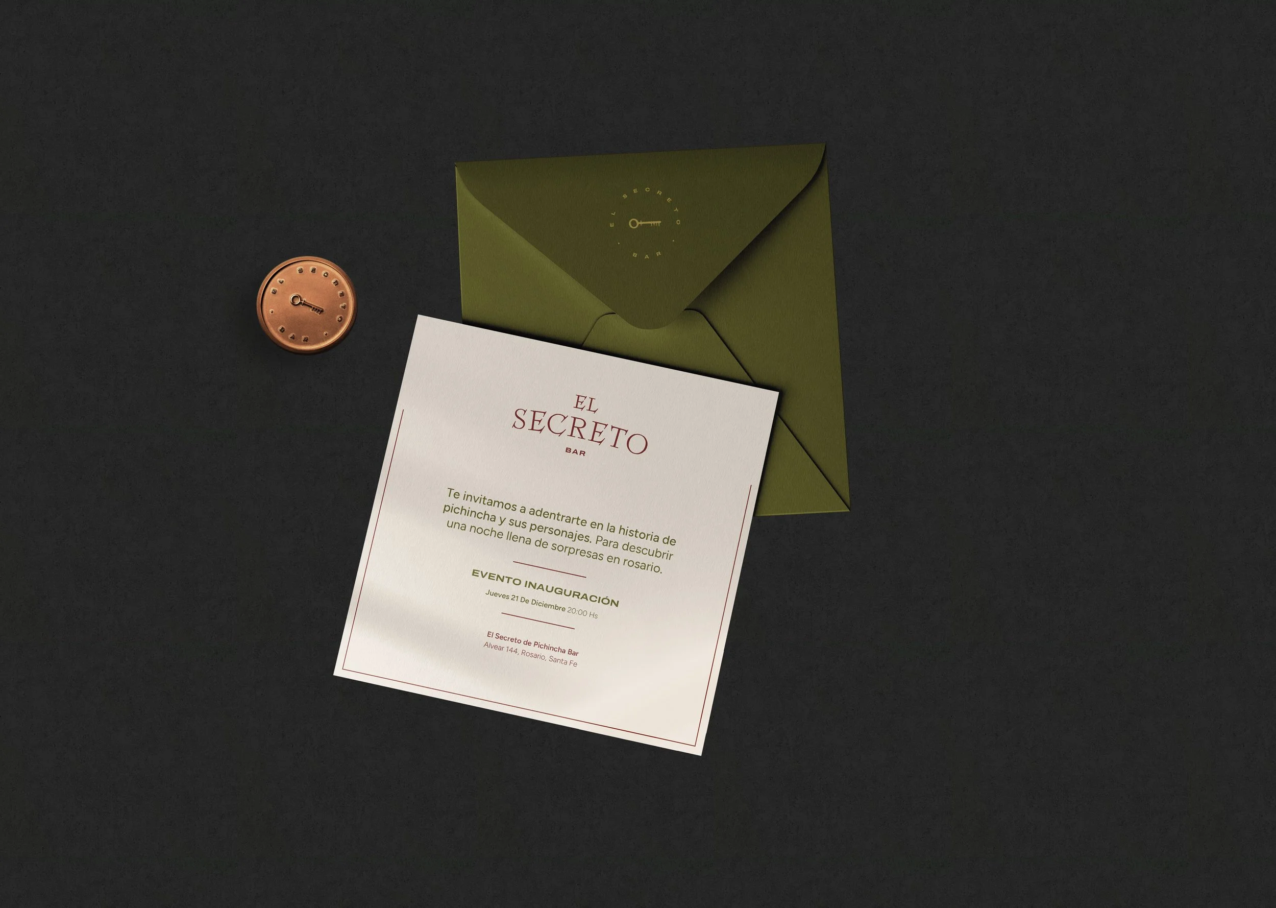 Invitación a evento en un bar llamado 'El Secreto'. Incluye una tarjeta en color blanco con texto en verde y rojo, una funda verde y un botón decorativo en forma de reloj con detalles en oro en un fondo negro.