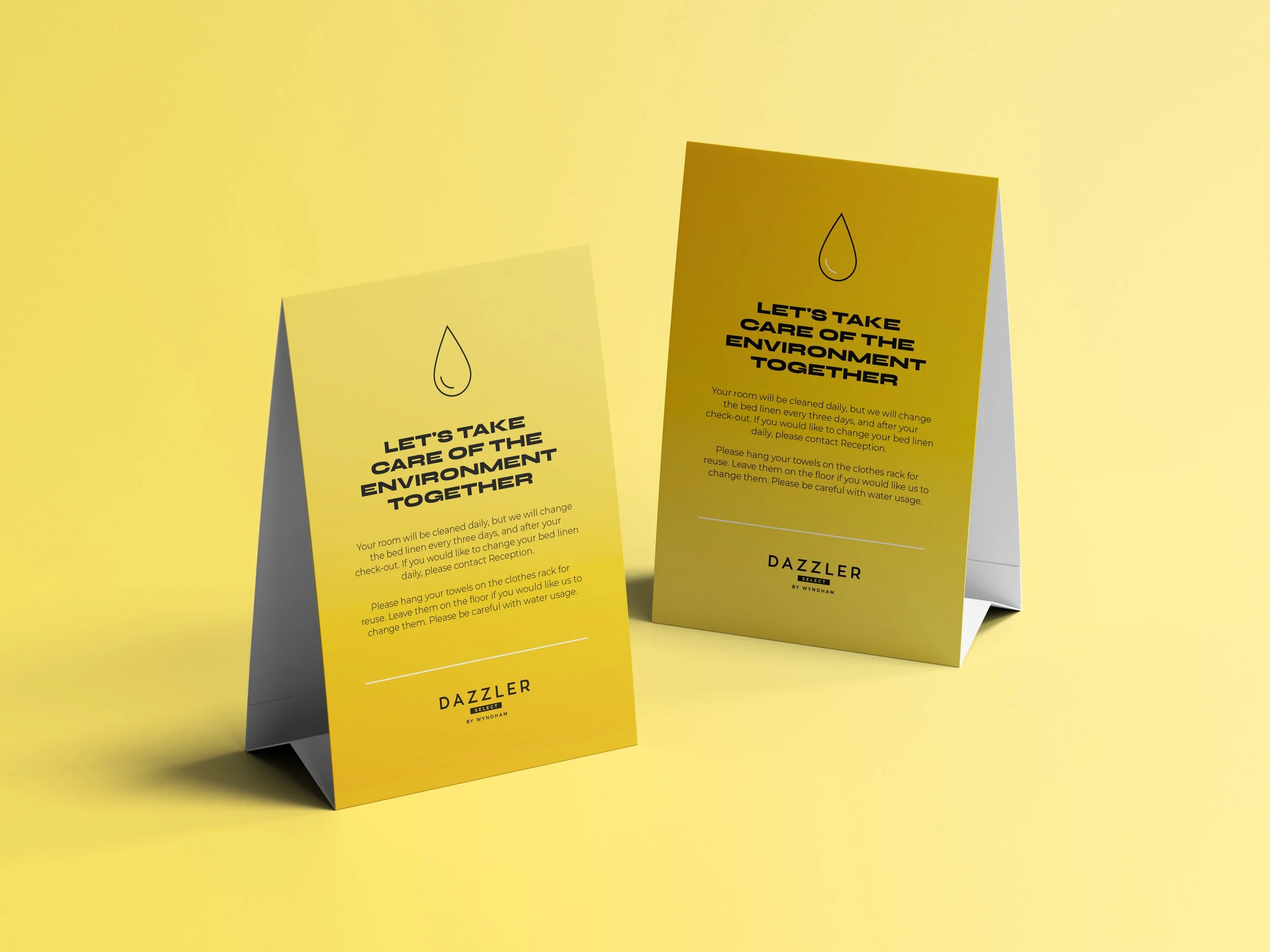 Dos carteles amarillos en forma de tríptico con instrucciones para cuidar el medio ambiente, con un dibujo de una gota de agua en la parte superior, colocados en una superficie amarilla.