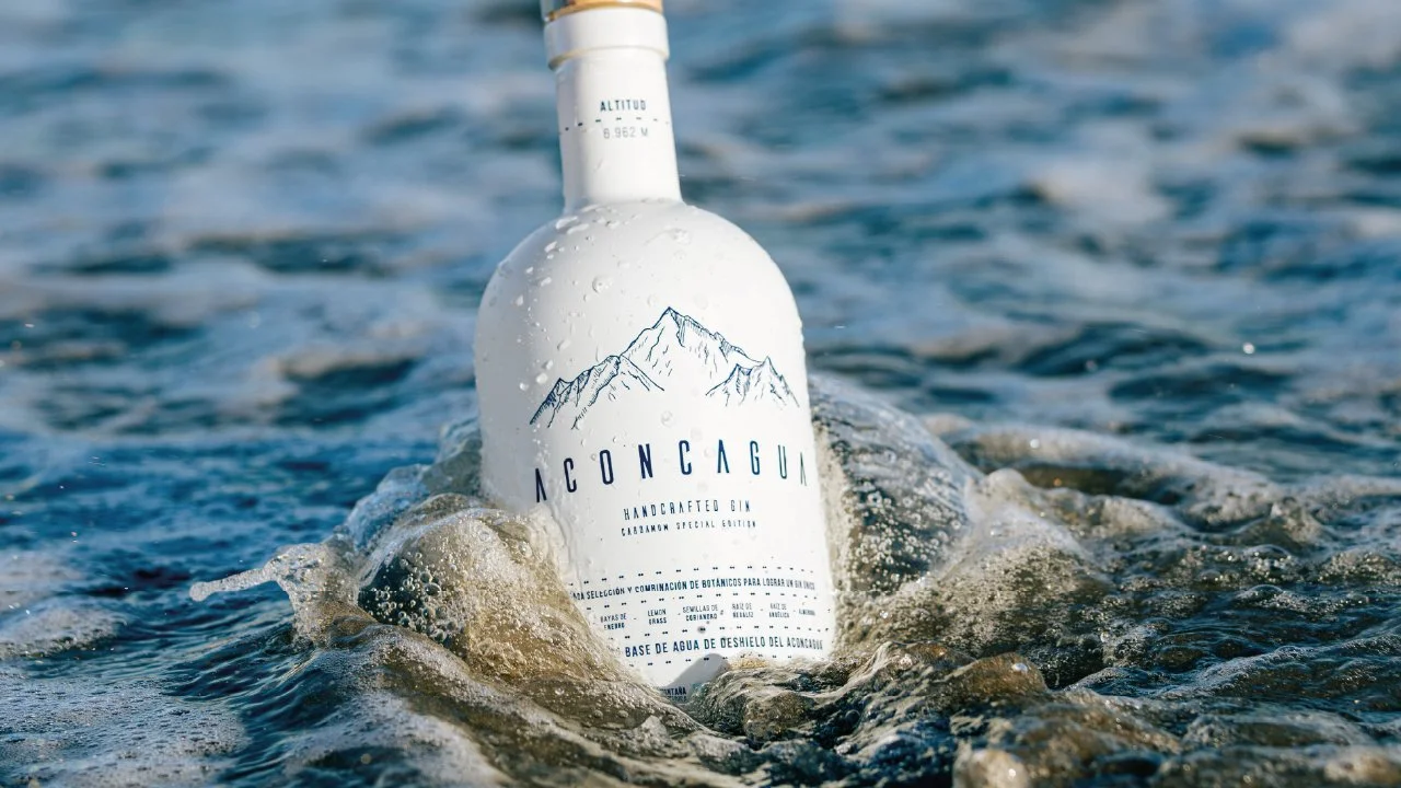Botella de gin artesanal Aconcagua flotando en el agua con olas y espuma