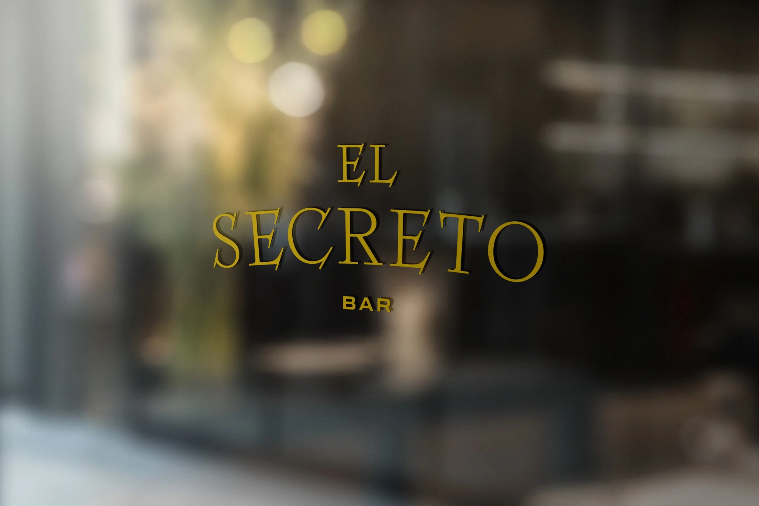 Puerta de un bar con el nombre 'El Secreto' en letras doradas.