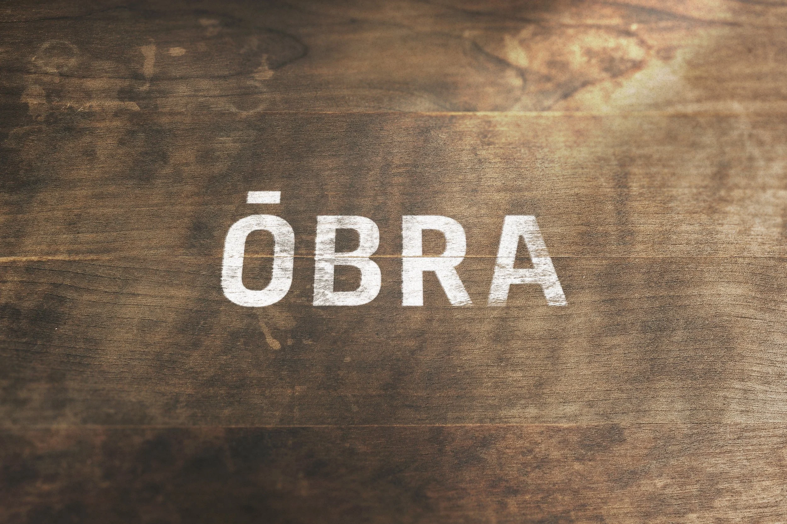 Palabra 'OBRA' escrita en letras blancas sobre una superficie de madera.
