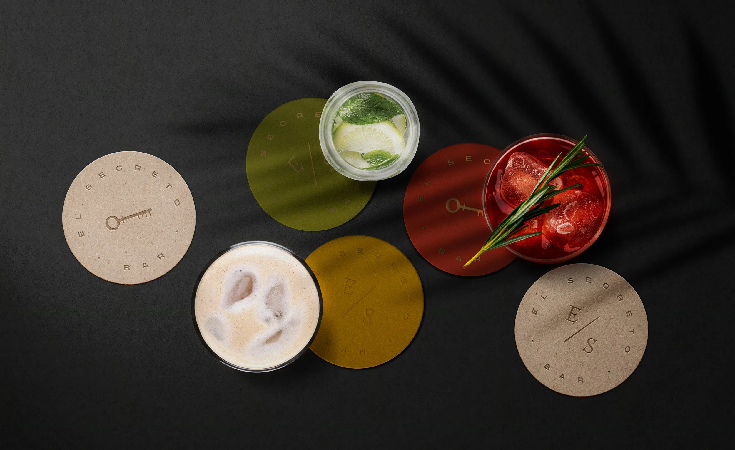 Una mesa con cinco bebidas diferentes, cada una con un filtro de colores, y algunos hielo en una de ellas.