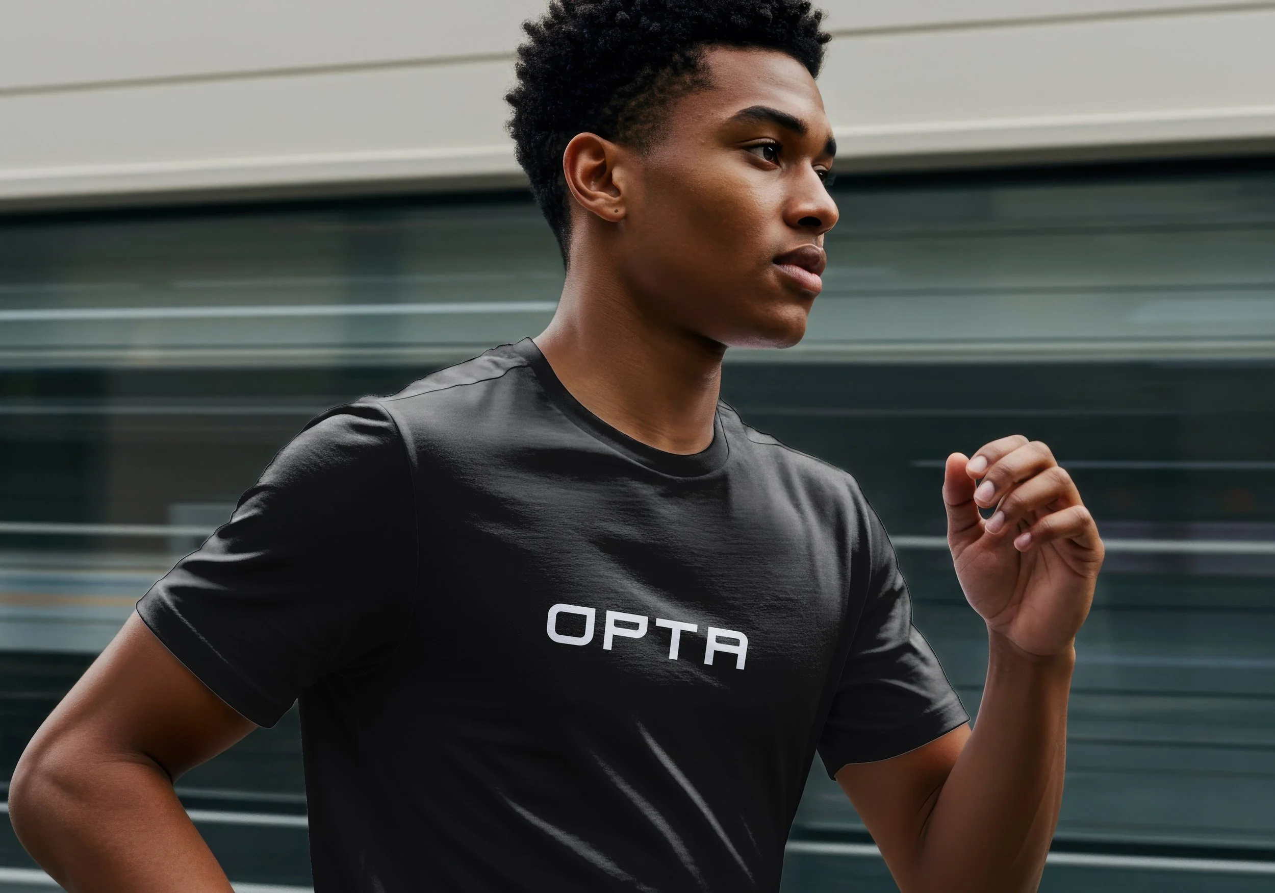 Joven mujer corriendo, usa camiseta negra con la marca 'OPTA' en el frente, fondo borroso en movimiento.