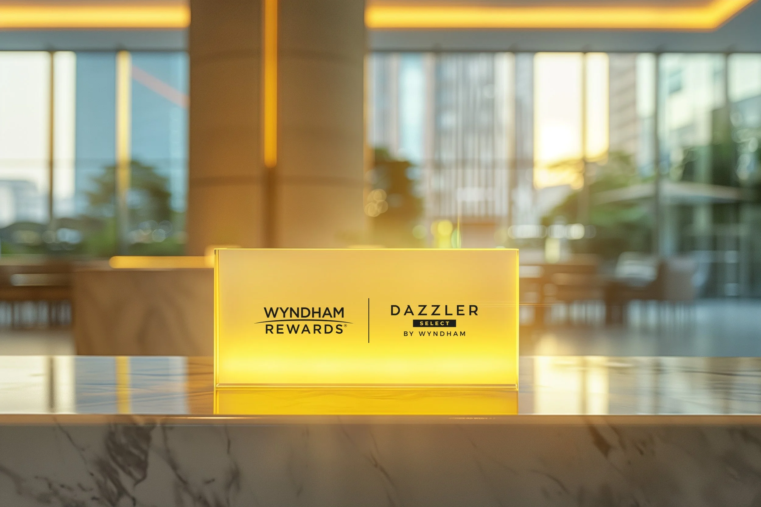 Tarjeta de recompensas Wyndham Rewards y Dazzler Select en un mostrador con fondo de ventanas y luz cálida.