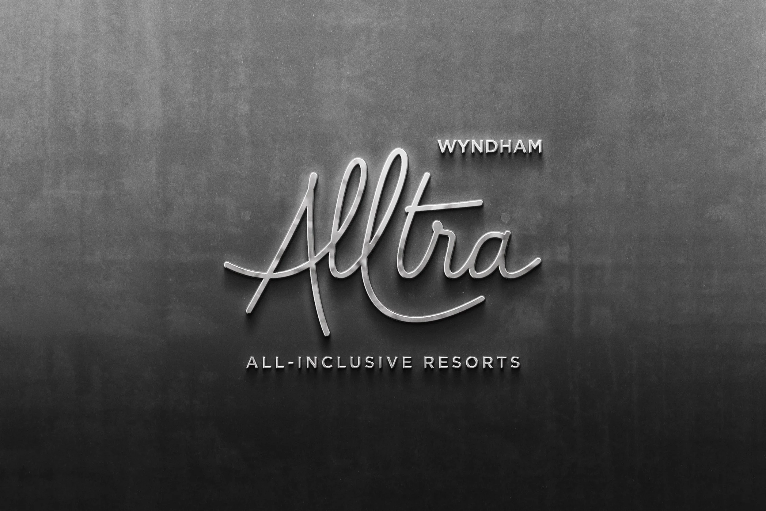 Refrigerado con letras en neón que dicen 'Altra Wyndham All-Inclusive Resorts' en pared gris.