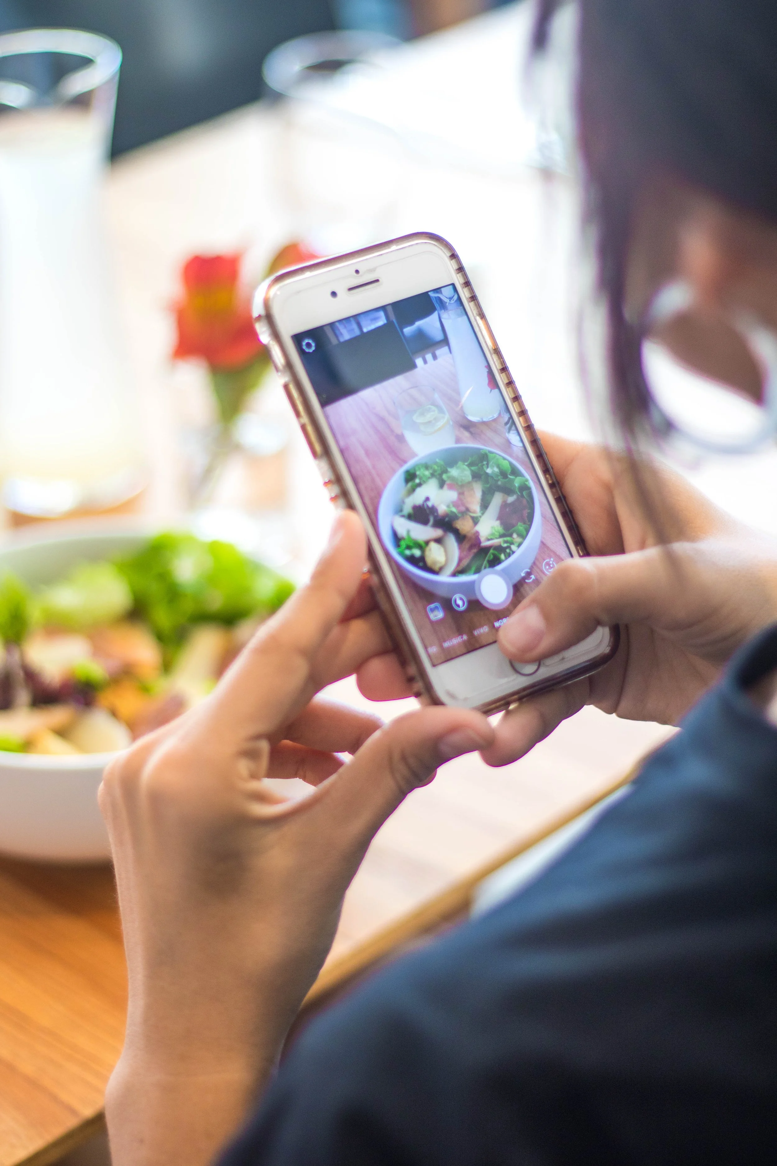 Persona tomando una foto de una ensalada en un restaurante.