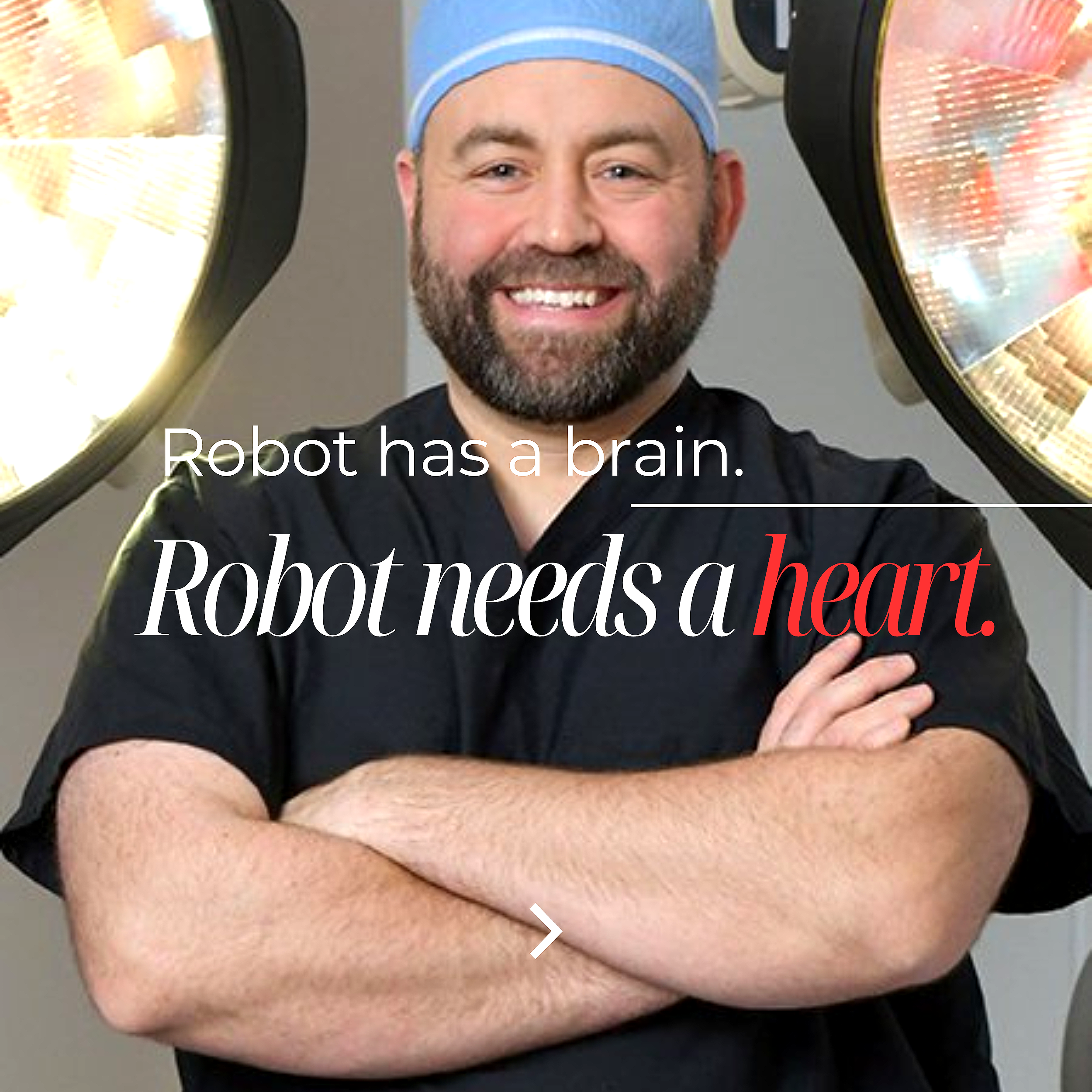 A man with a beard smiling, wearing a cap, with robotic eyes, standing with crossed arms against a plain background.