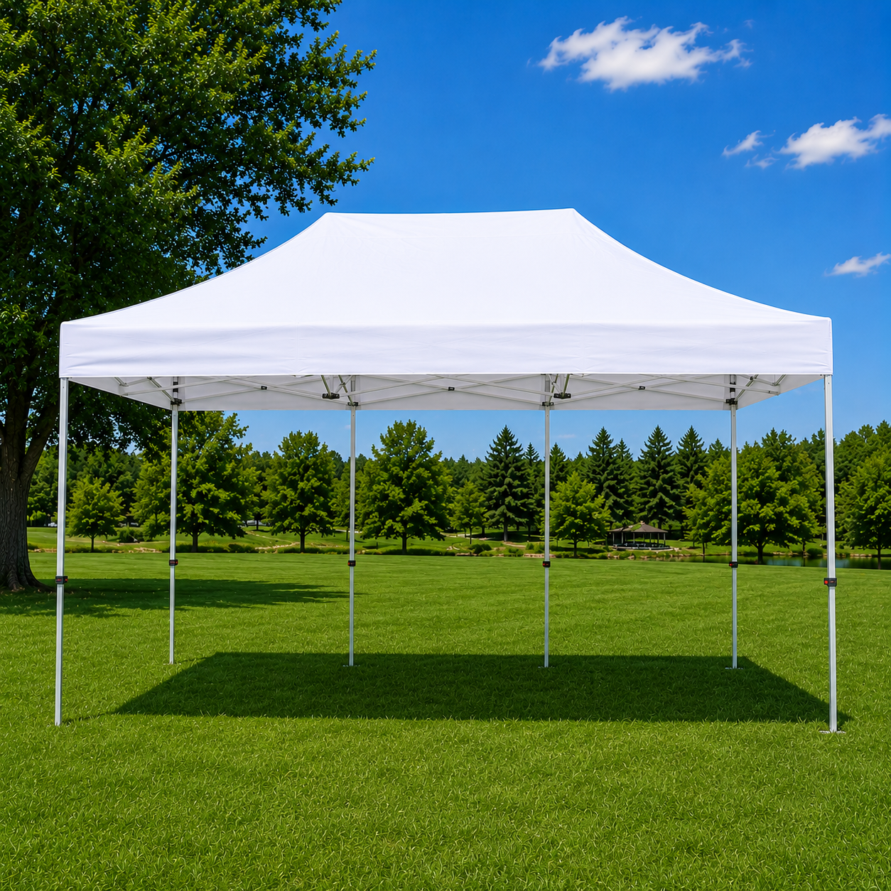 A white canopy tent set up in a grassy park with trees and a blue sky with a few clouds in the background.