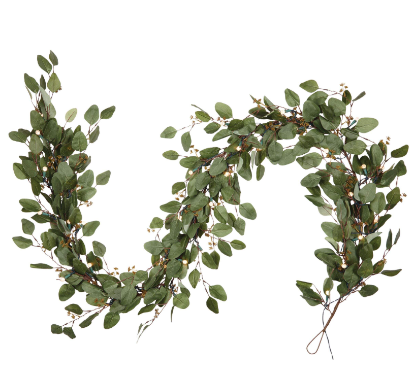 Decorative green leafy garland with small string lights on a white background.