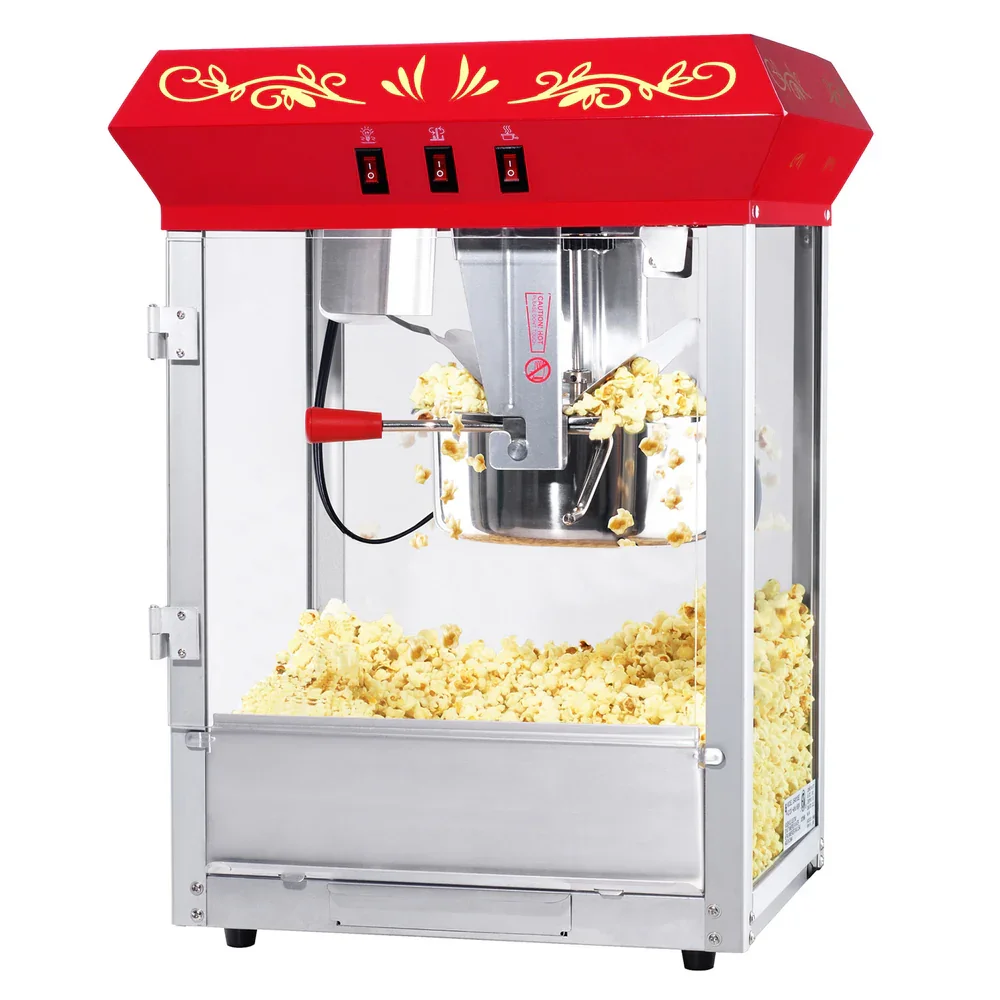 Electric popcorn machine with red and gold decorative top, producing popcorn inside a glass enclosure.