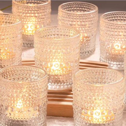Multiple lit candles in textured glass holders arranged on a tray.