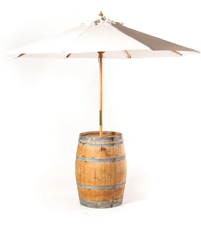A large white patio umbrella with a wooden pole, placed in a wooden barrel, against a plain white background.