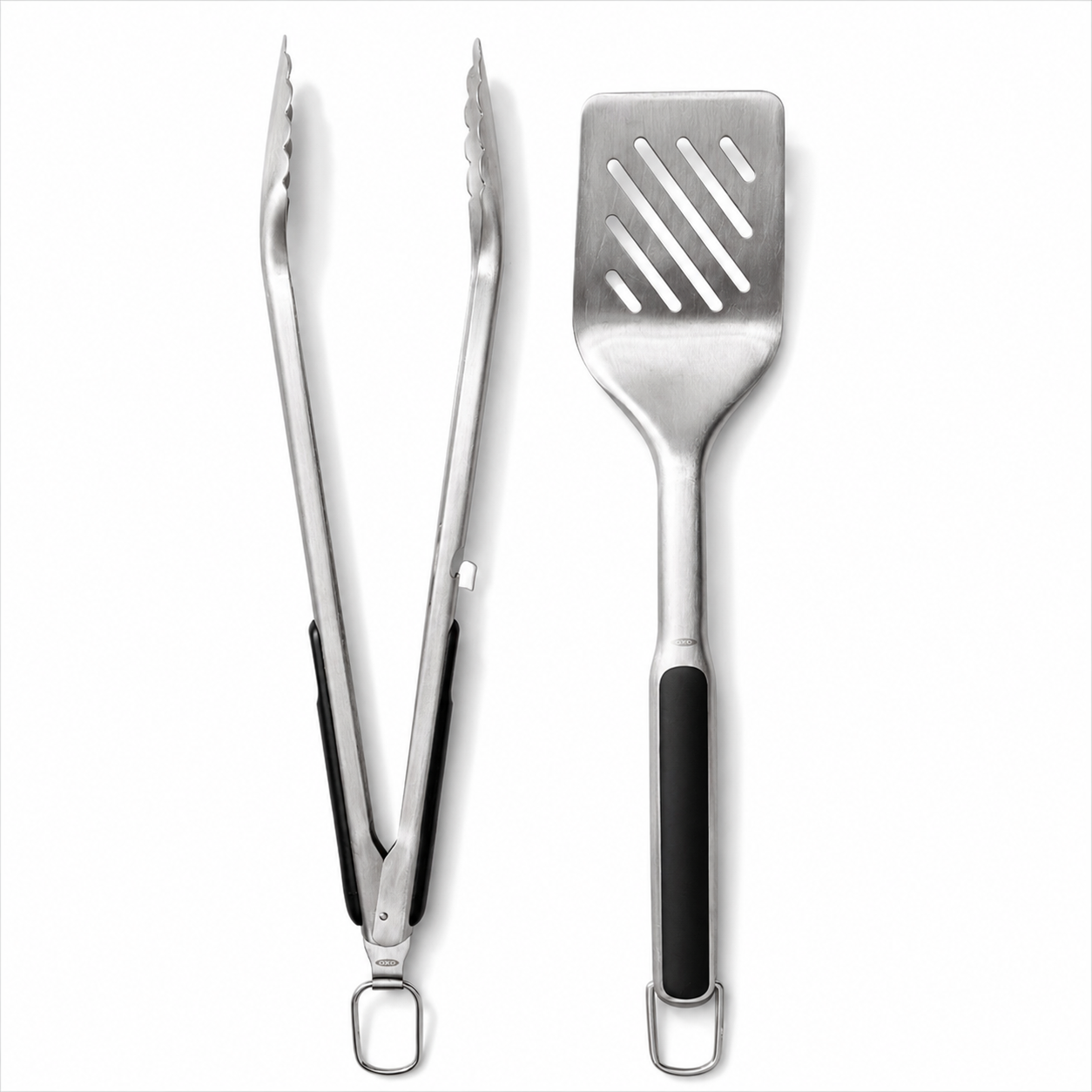 Stainless steel kitchen tongs and slotted spatula on a white background.