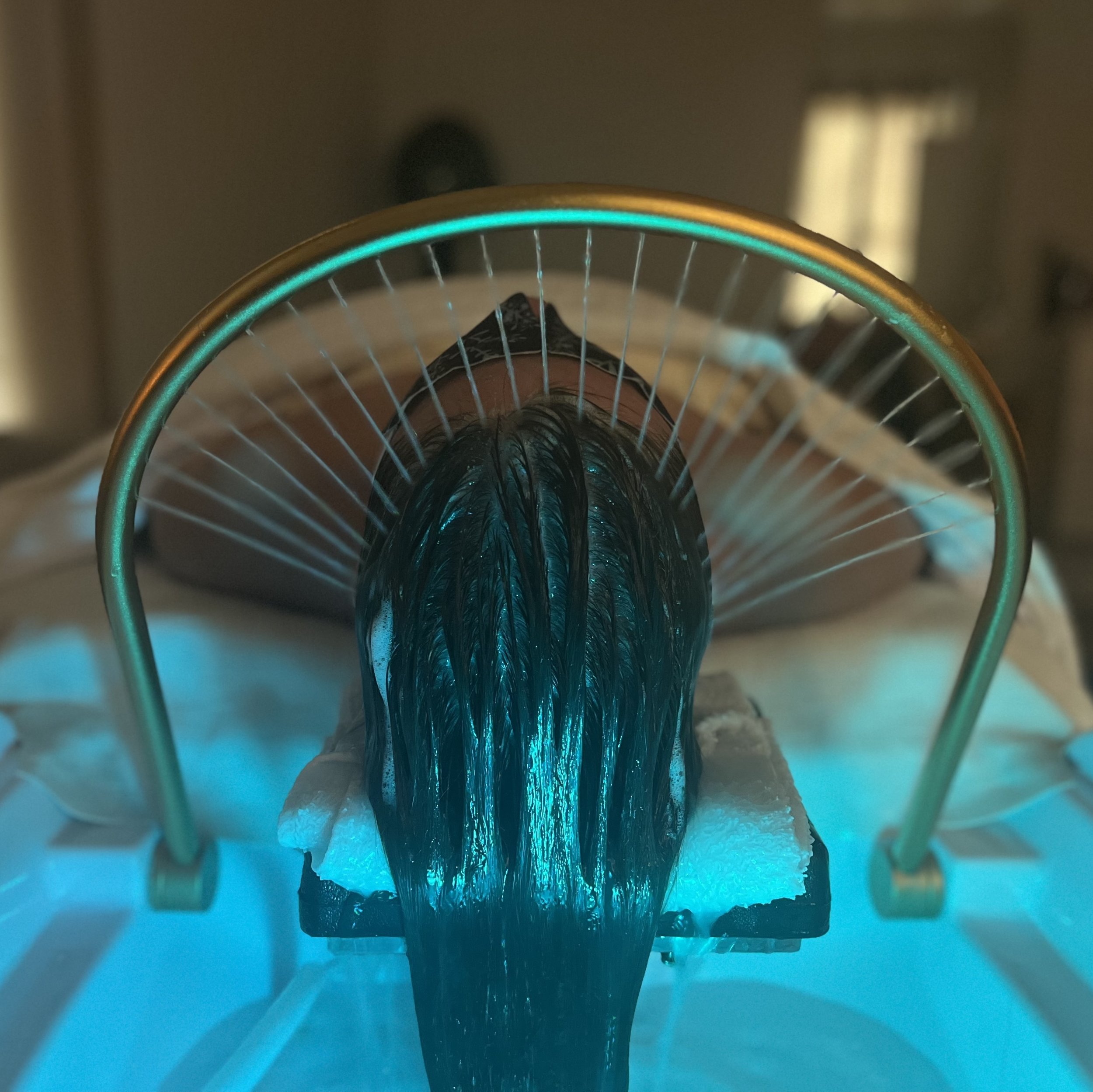 arch of water flowing over relaxed woman during head spa