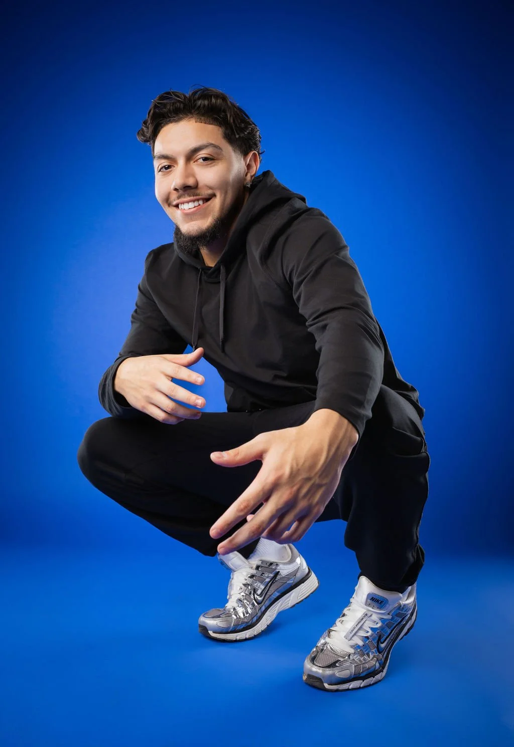 A Willow Canyon High School senior in Surprise, Arizona kneeling down in front of a blue backdrop