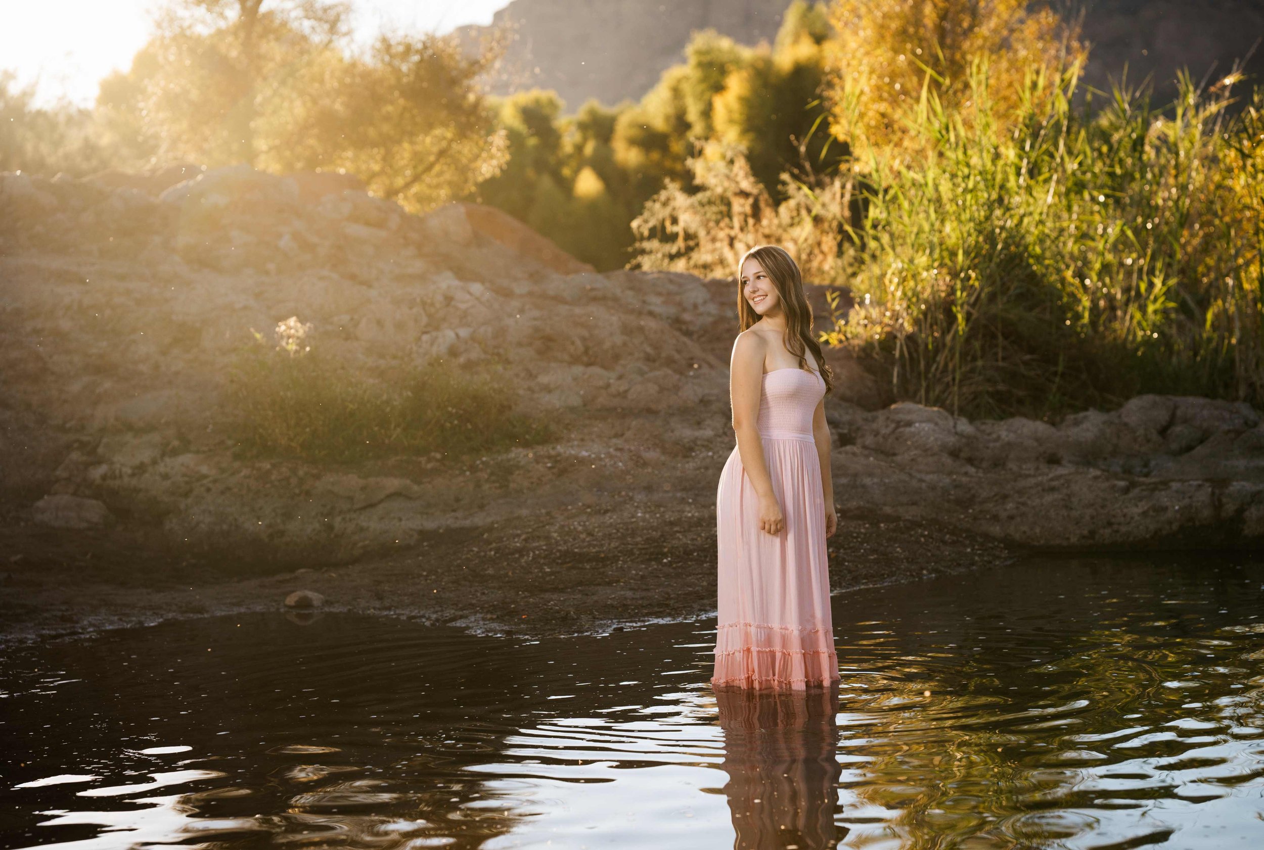 A young woman standing in the water during her senior session at the Salt River