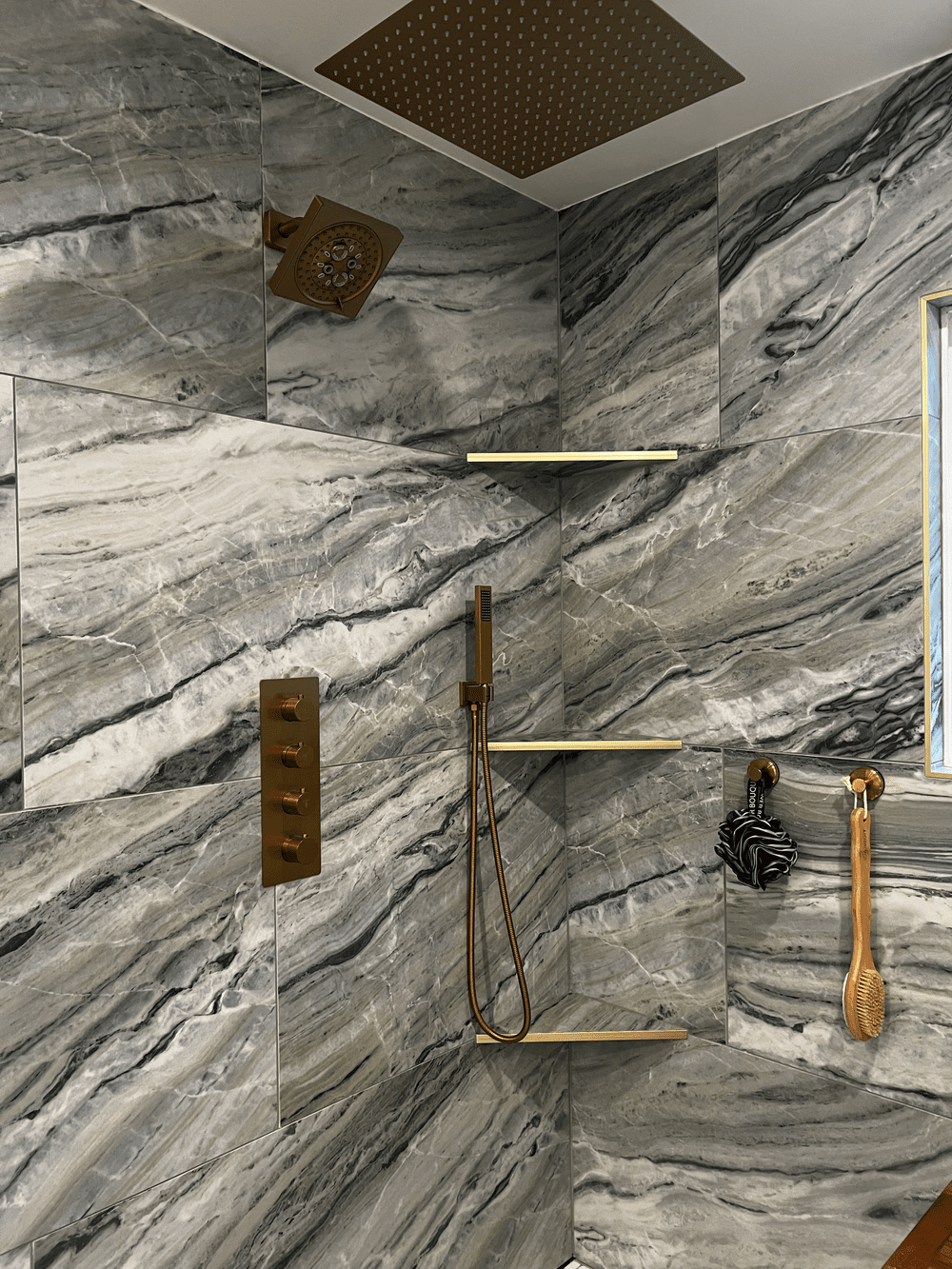 Shower with marbled gray and white tile and gold fixtures