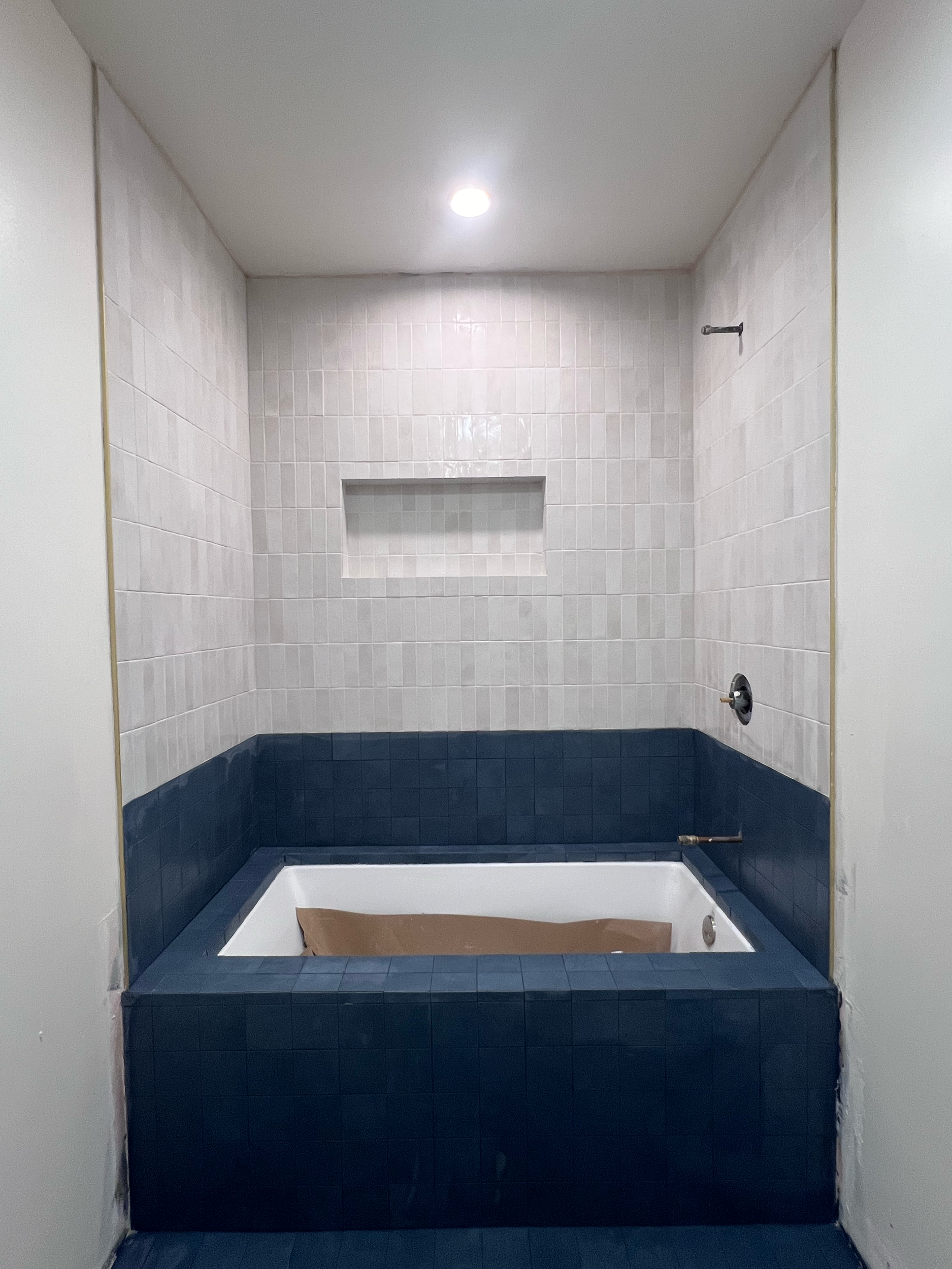 Bathroom with a bathtub and tiled wall, under construction or renovation.