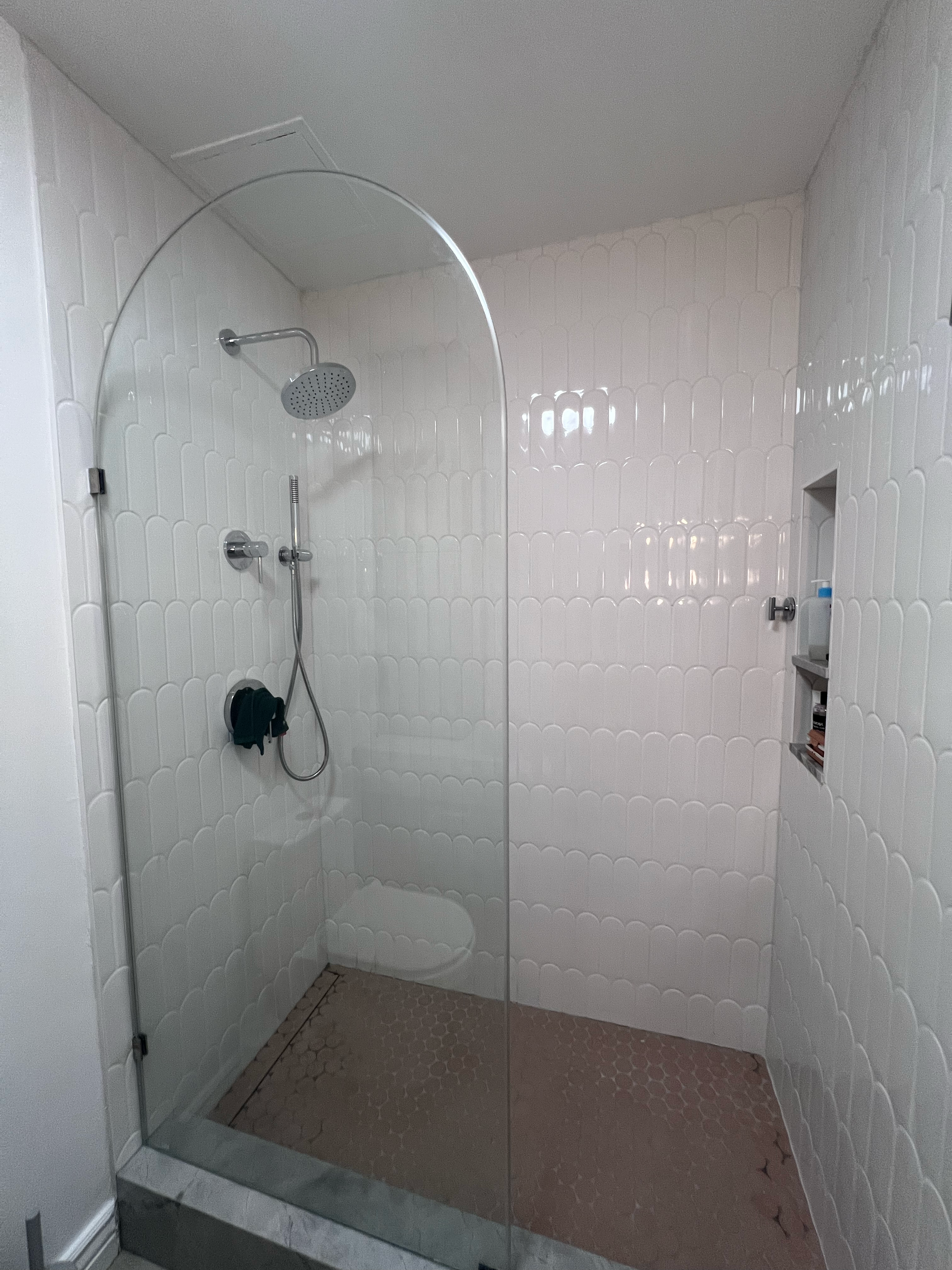 Walk-in shower remodel with a clear glass door, chrome showerhead and white tiled walls