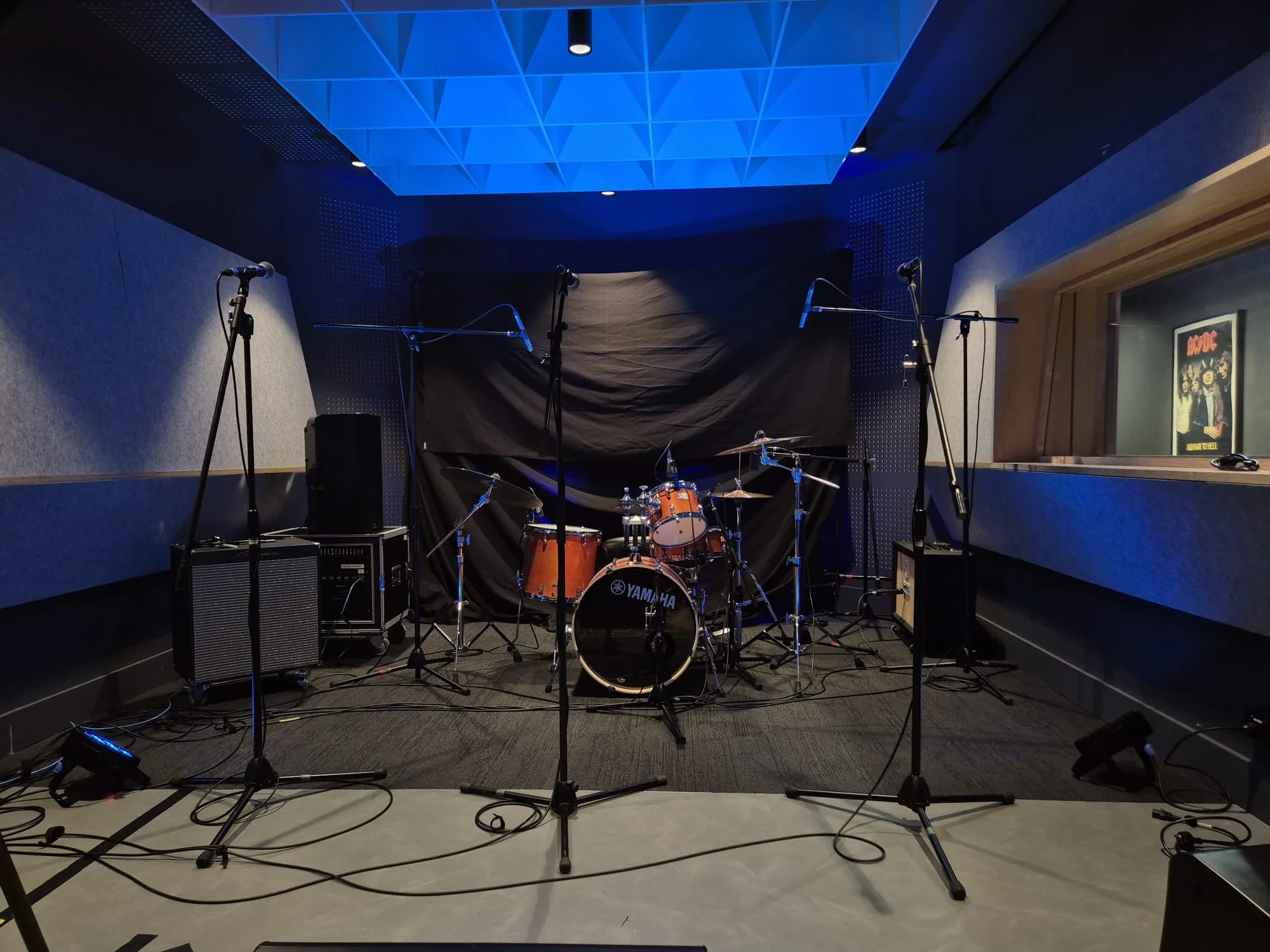 Empty music stage with drum set and multiple microphones in a recording studio.