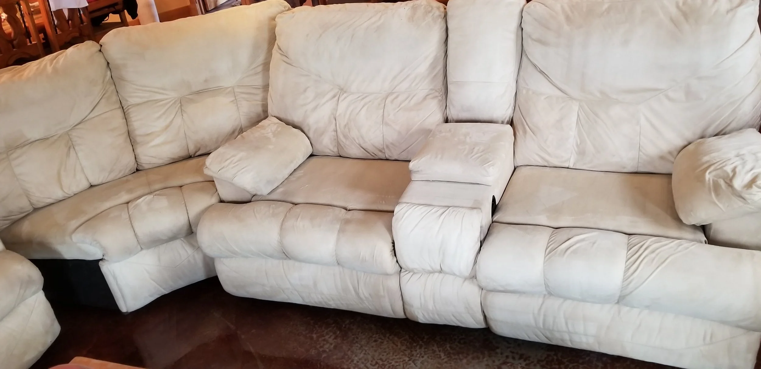 Cream-colored sectional sofa with cushioned seats and pillows in a furniture store.