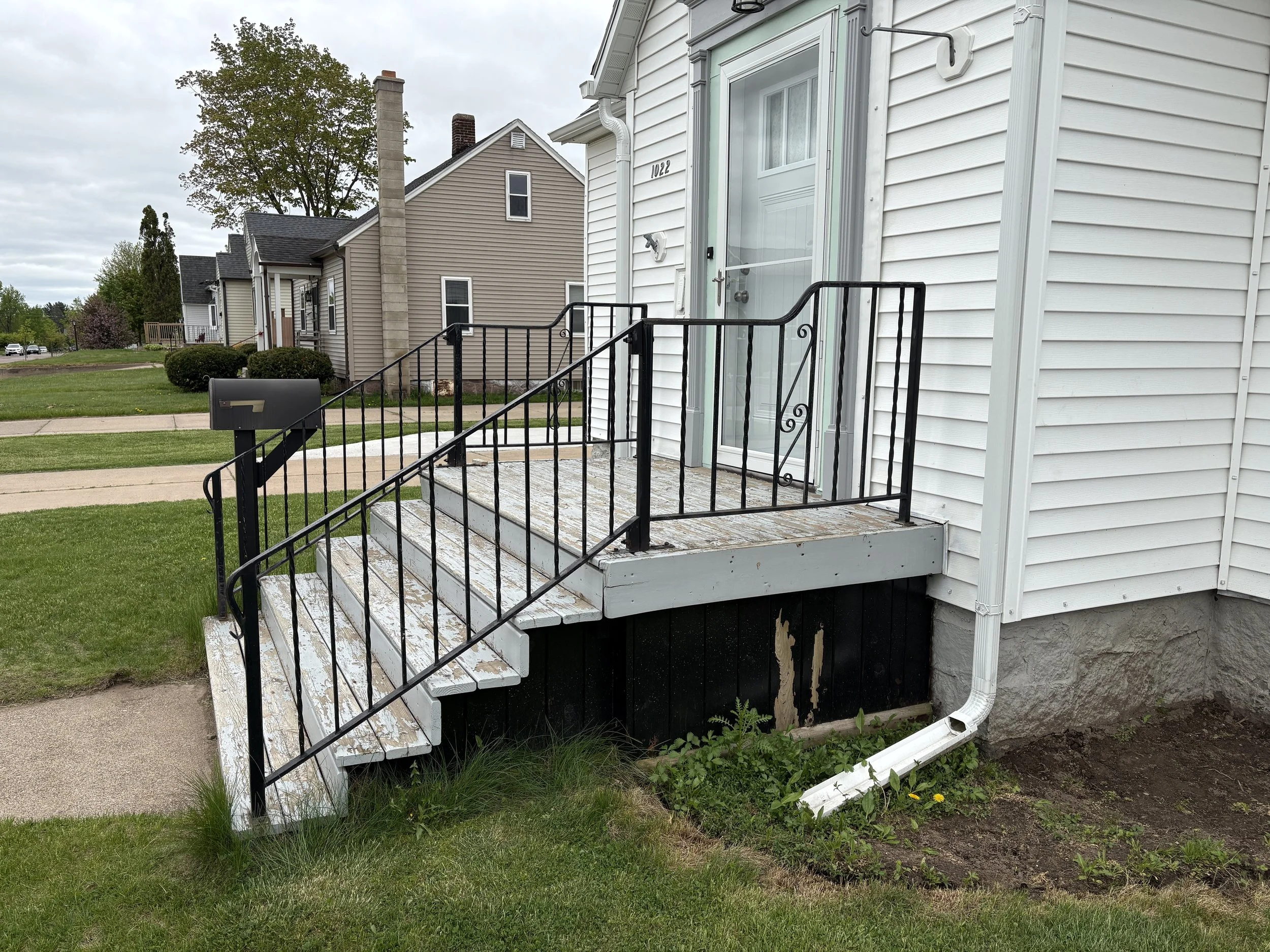 Before porch renovation with worn wooden steps and metal railing on a home in Central Wisconsin.