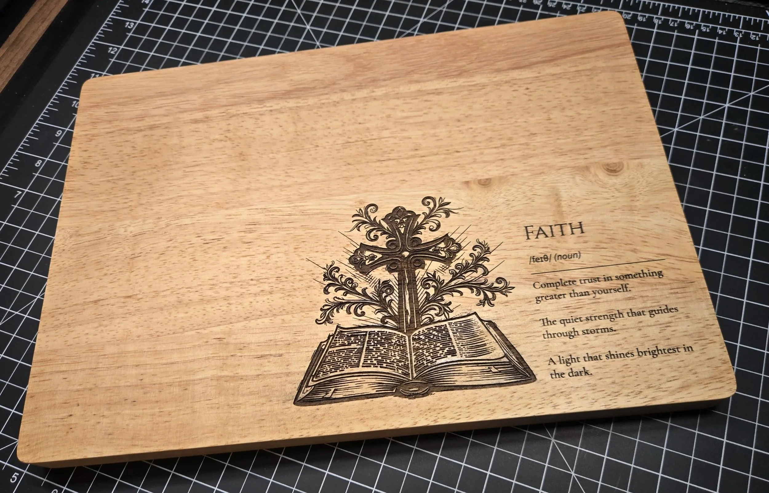 Wooden plaque with a printed illustration of a tree growing from an open book, alongside a definition and description of the word 'faith'.