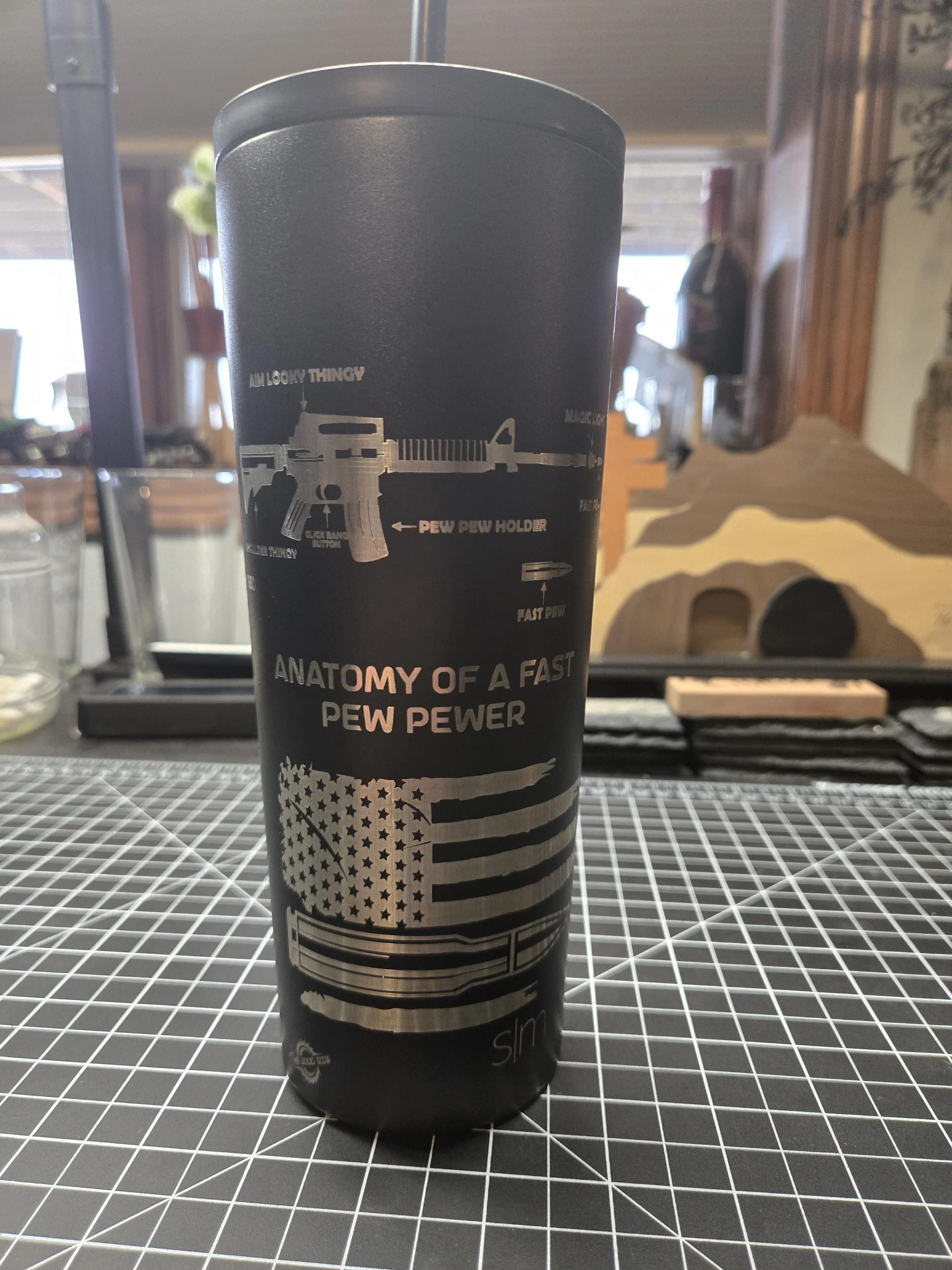 A black cylindrical container with a design and text about guns and American patriotism, featuring a stylized American flag and a firearm illustration.